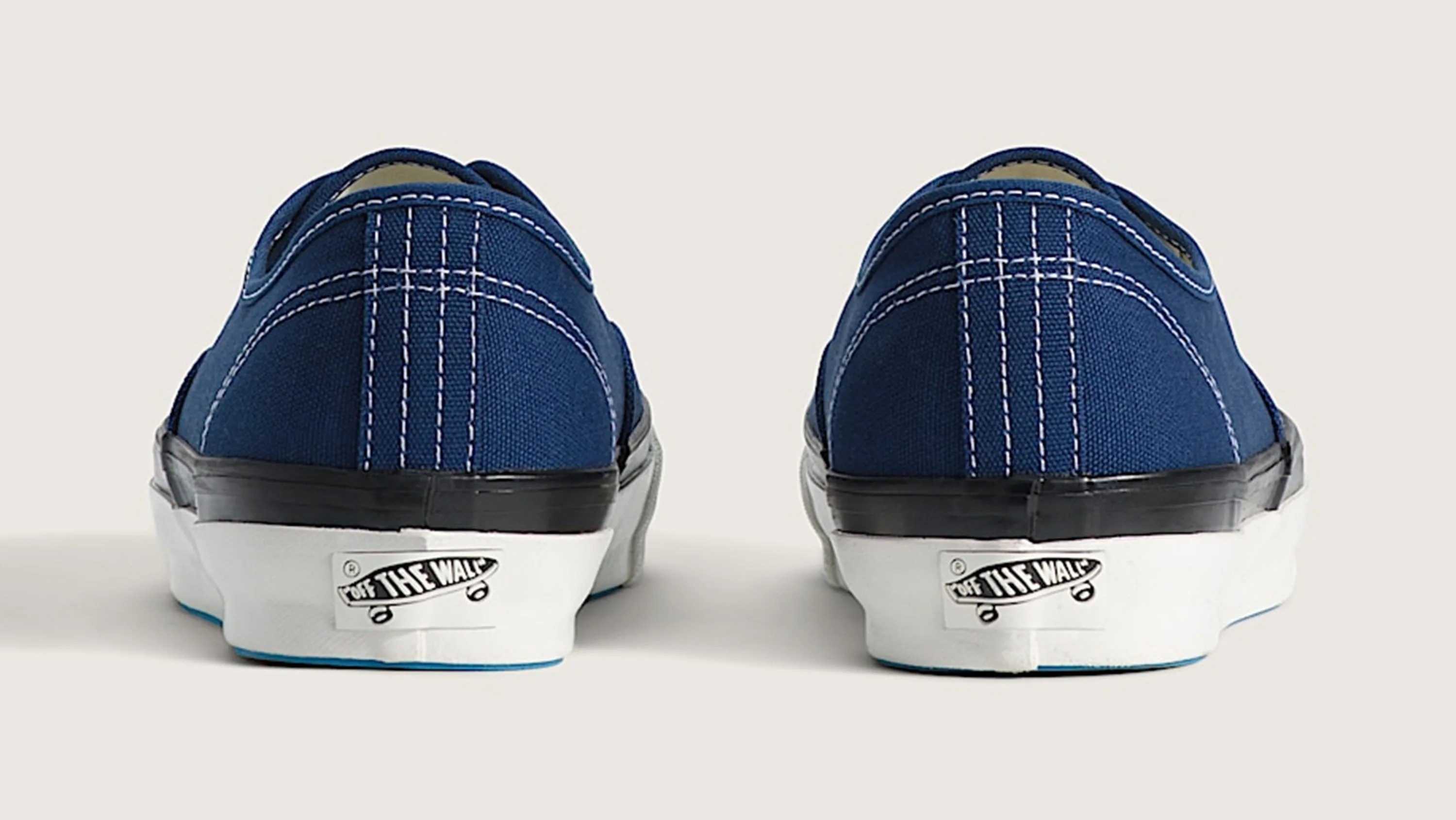 Pair of navy blue canvas Vans sneakers viewed from the back showing white soles with "Off The Wall" logo.