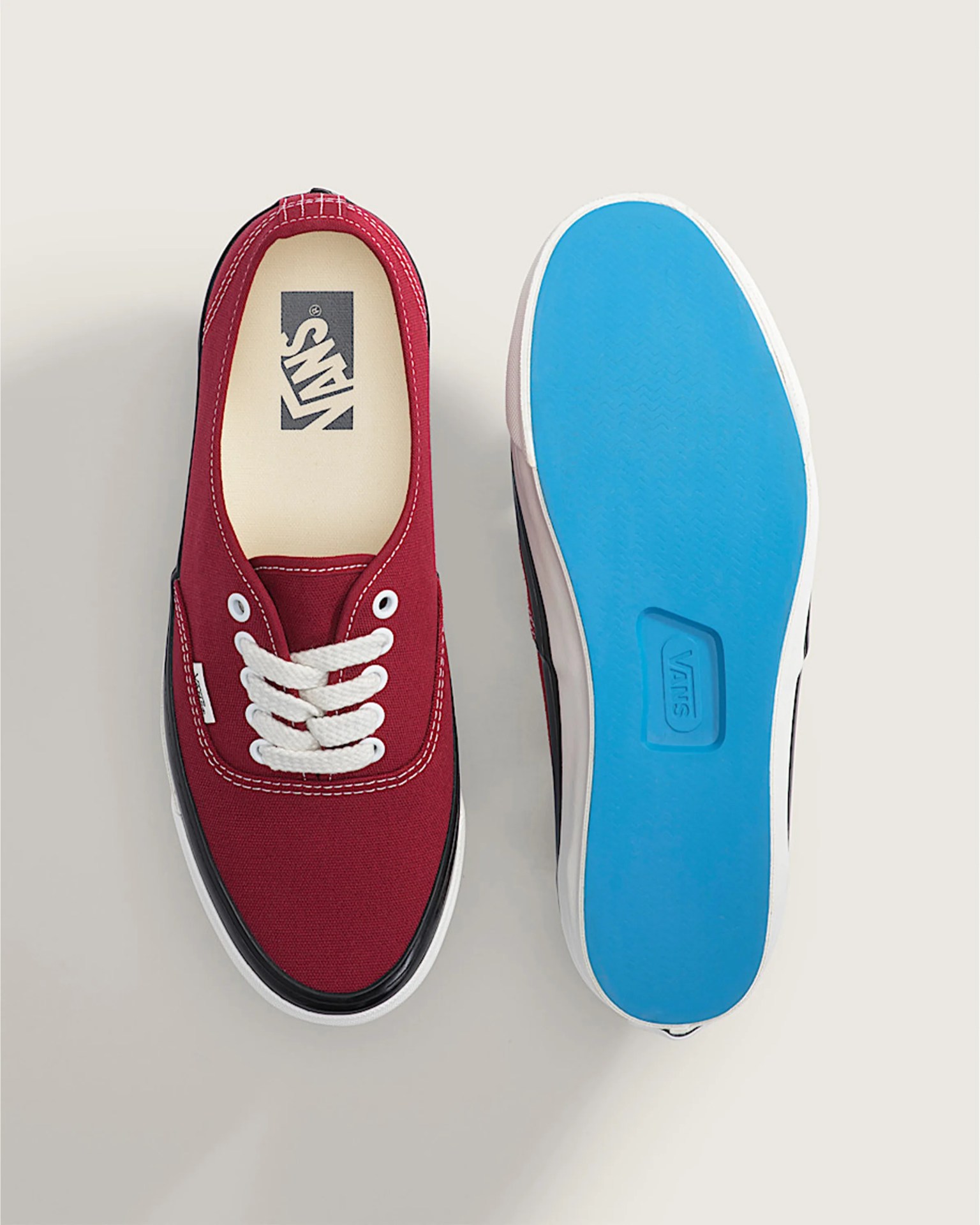 Pair of red Vans sneakers with white laces, black trim, and bright blue soles shown from top and bottom.