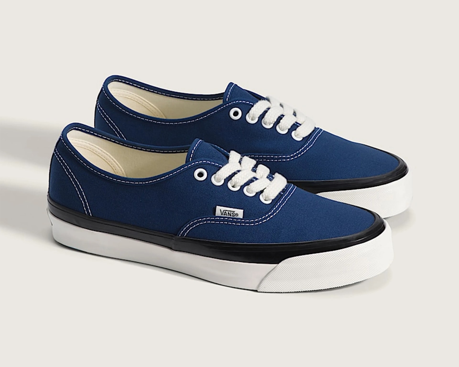 Pair of navy blue Vans sneakers with white laces, white soles, and black trim.