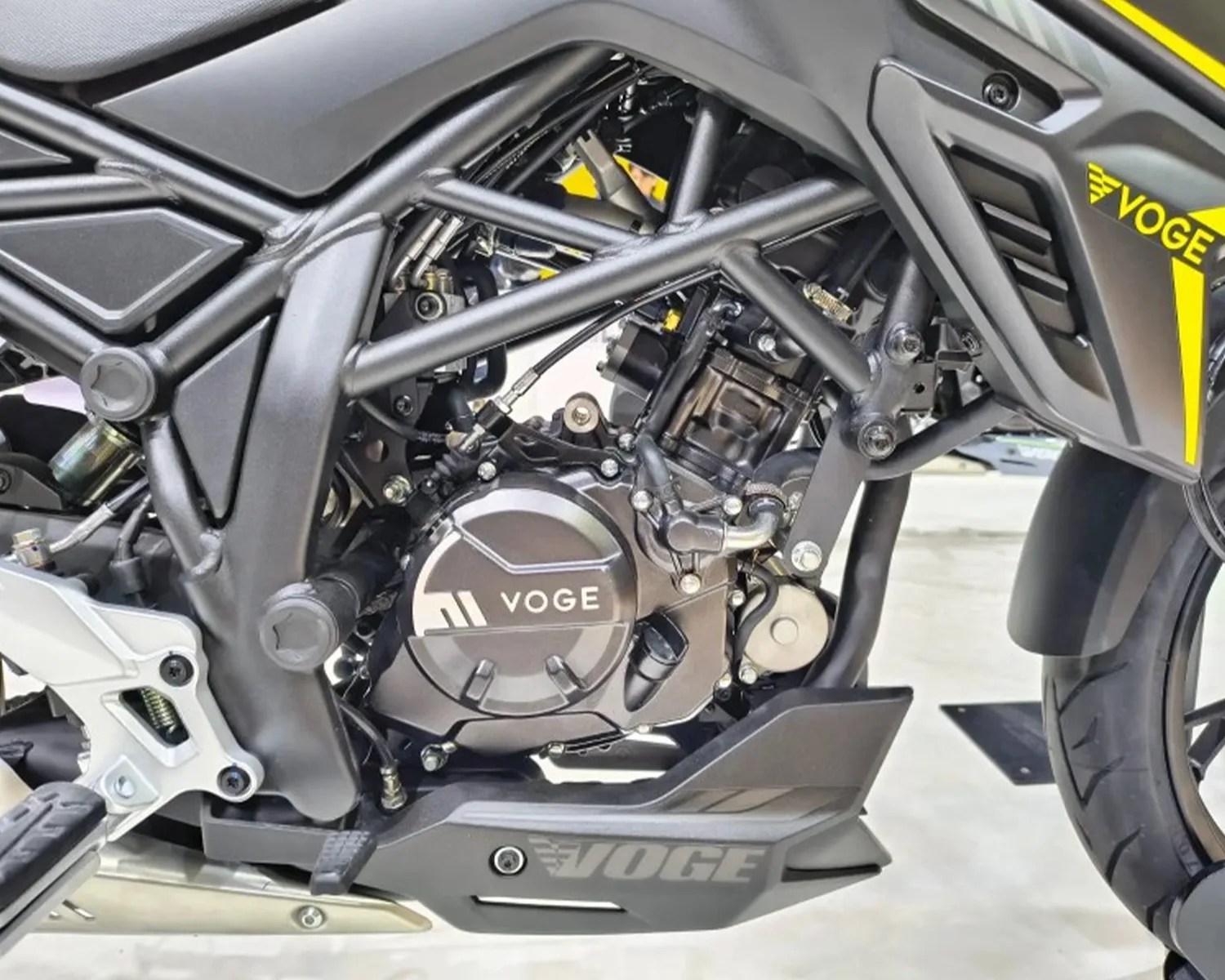Close-up of a black Voge motorcycle engine and frame with yellow accents on the body panel.