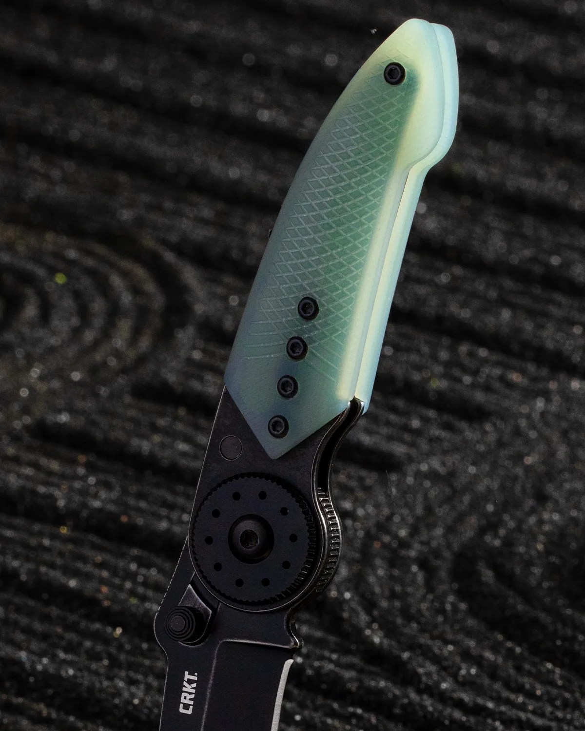 Folding knife with a black blade and a textured translucent green handle, branded CRKT.