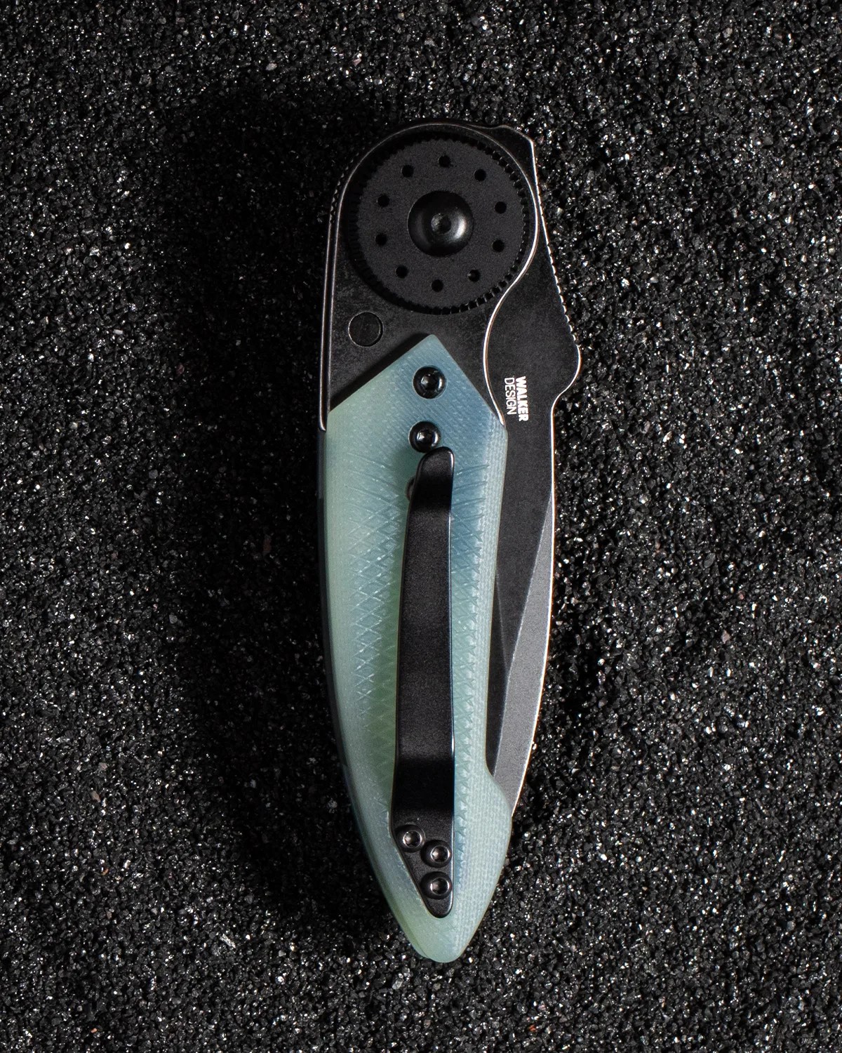 Folded pocket knife with a translucent light blue handle and black clip on a textured black surface.