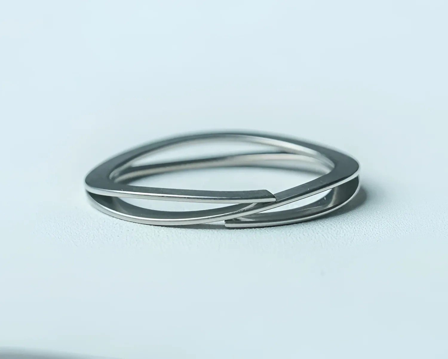 Polished silver geometric bracelet with overlapping triangular shapes on a white surface.