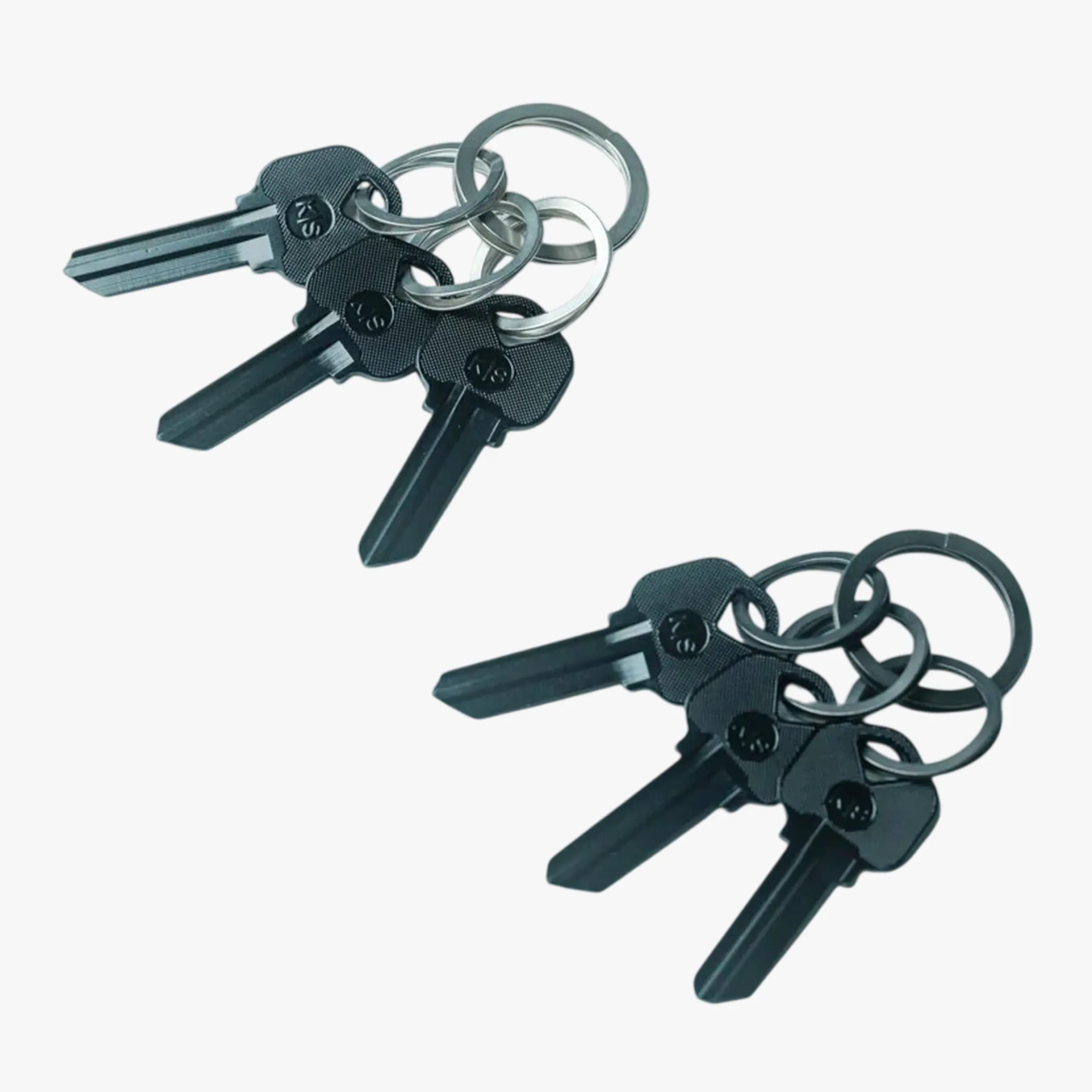 Two sets of three black plastic-headed keys on silver and black key rings.
