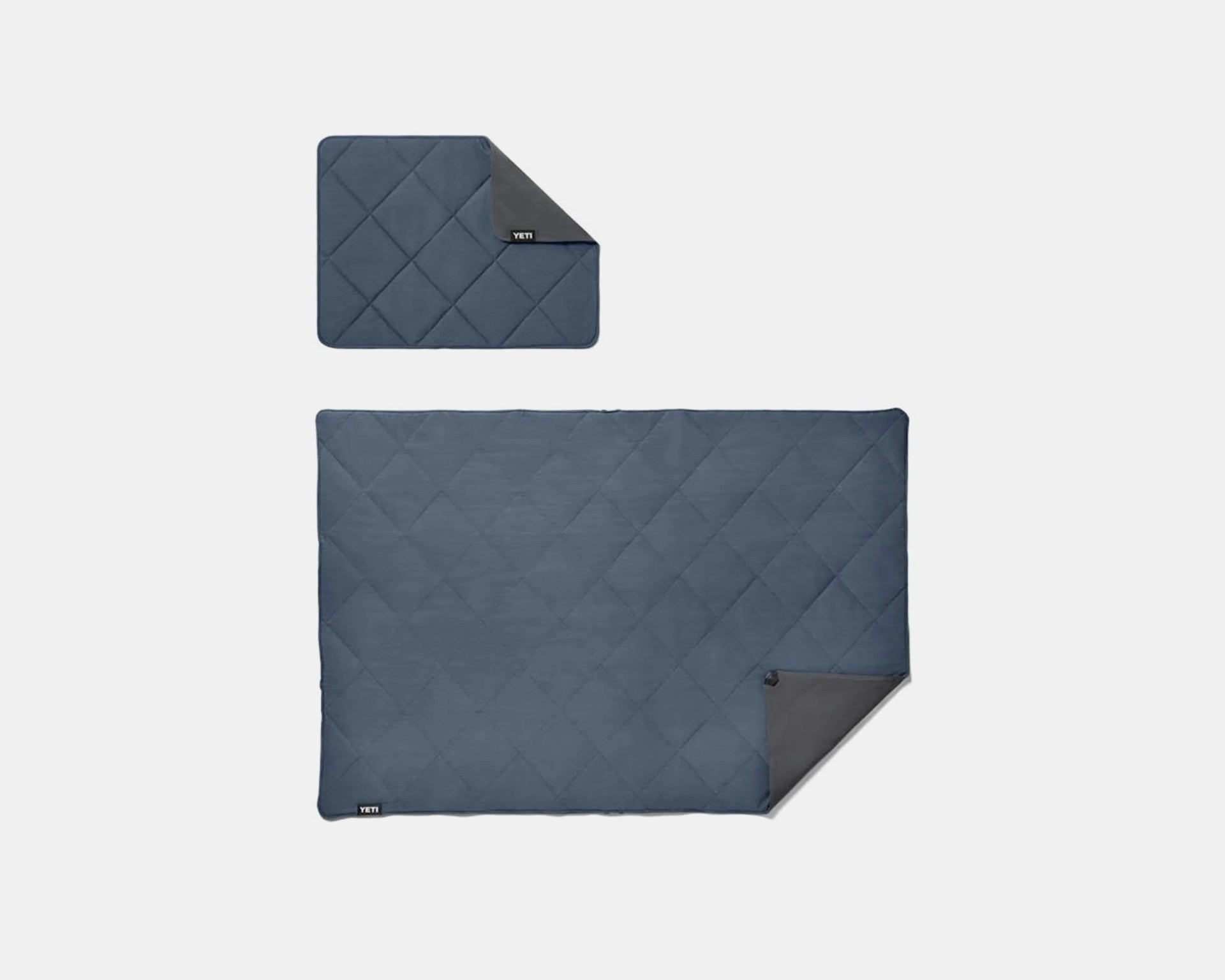 Two blue quilted YETI blankets with dark gray backing, one large and one small, laid flat on a white background.