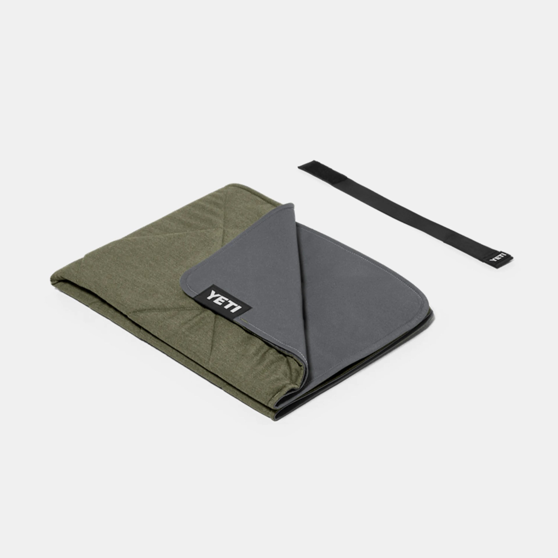 Folded olive green and gray YETI insulated blanket with a black strap on a white background.