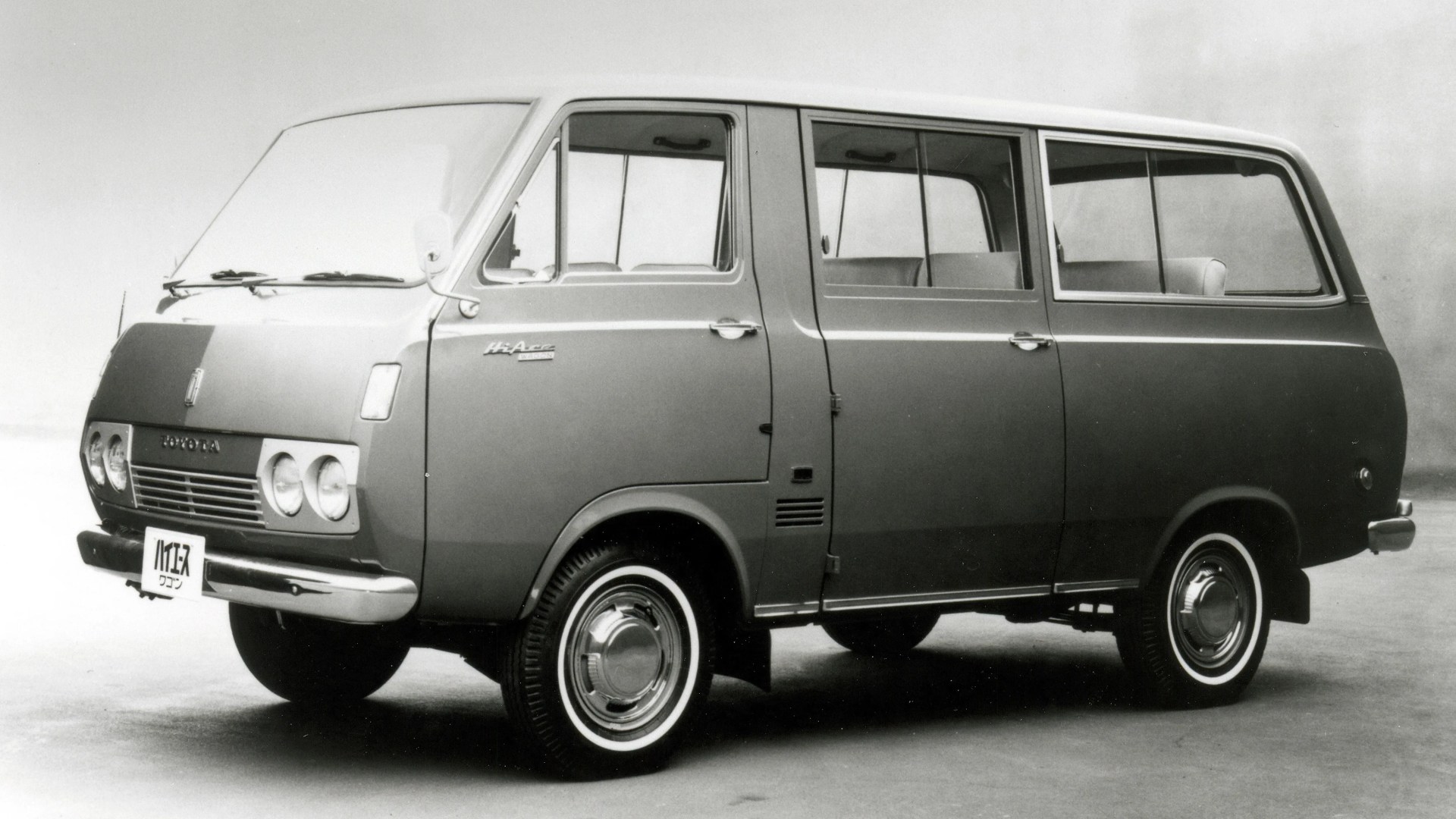 Black and white photo of a vintage Toyota HiAce van with dual round headlights and whitewall tires.
