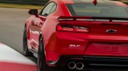 Red Chevrolet Camaro ZL1 with black racing stripes driving on a racetrack.