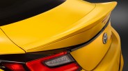Yellow Toyota car rear with a raised spoiler and red tail light on a dark background.
