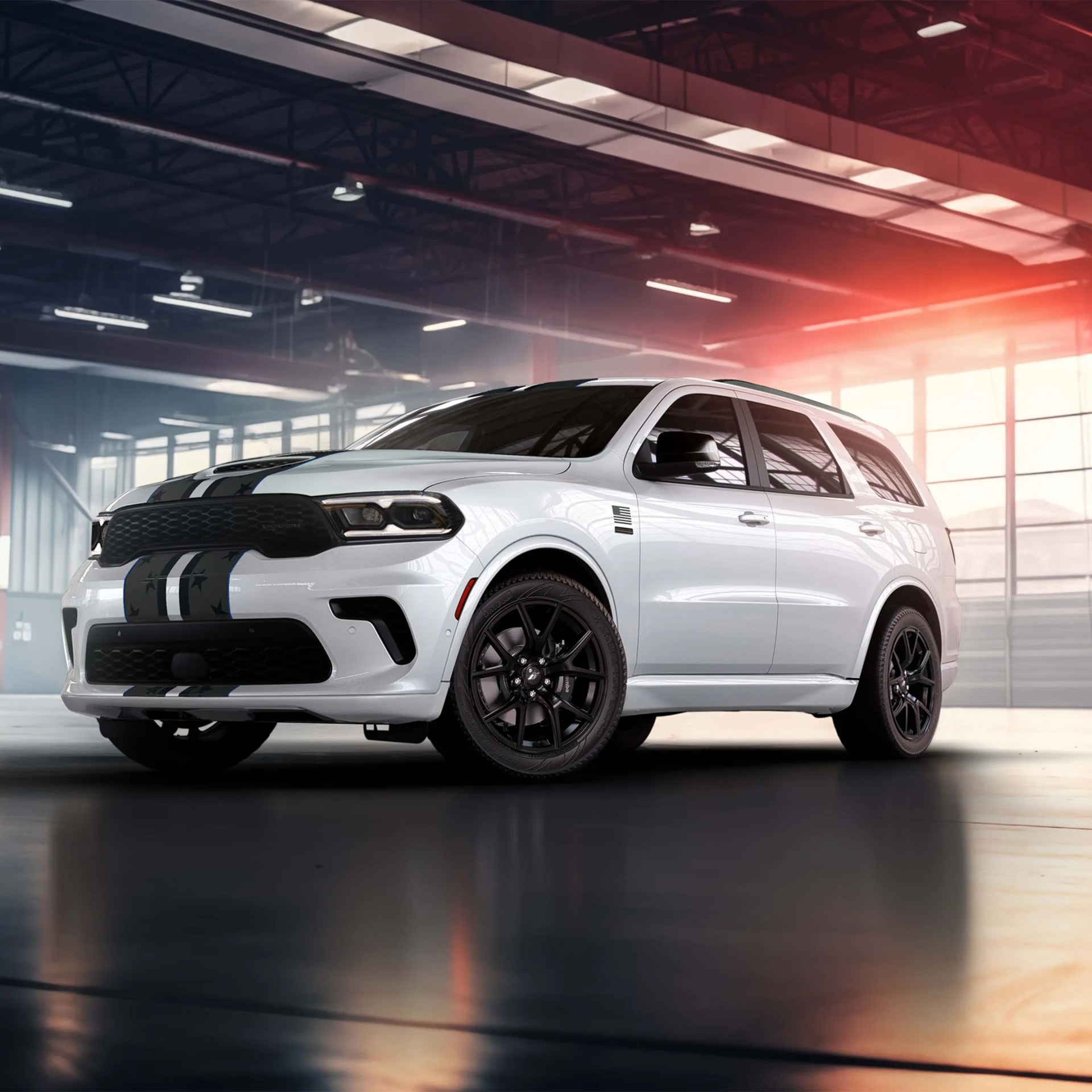 White SUV with black racing stripes and black wheels parked inside a large industrial garage.