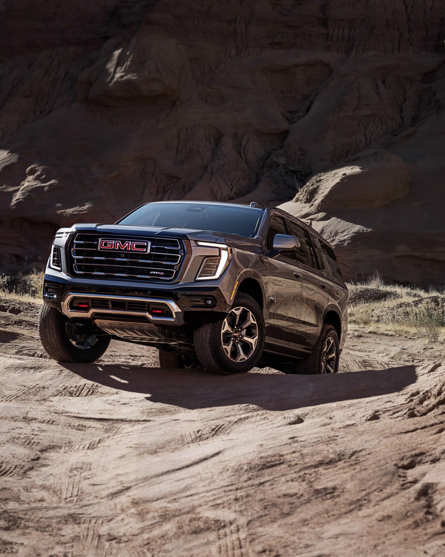 Black GMC SUV with chrome grille and red accents parked on rocky desert terrain.