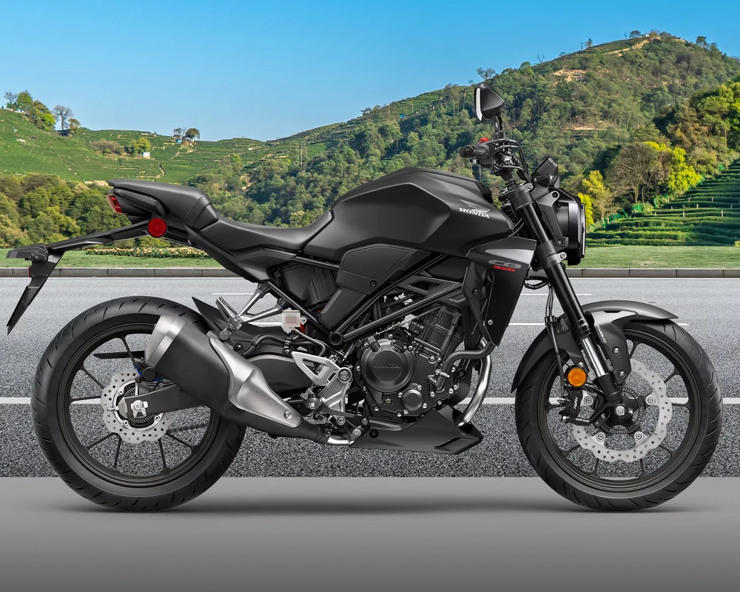 Matte black Honda CB300R motorcycle parked on a road with green hills in the background.