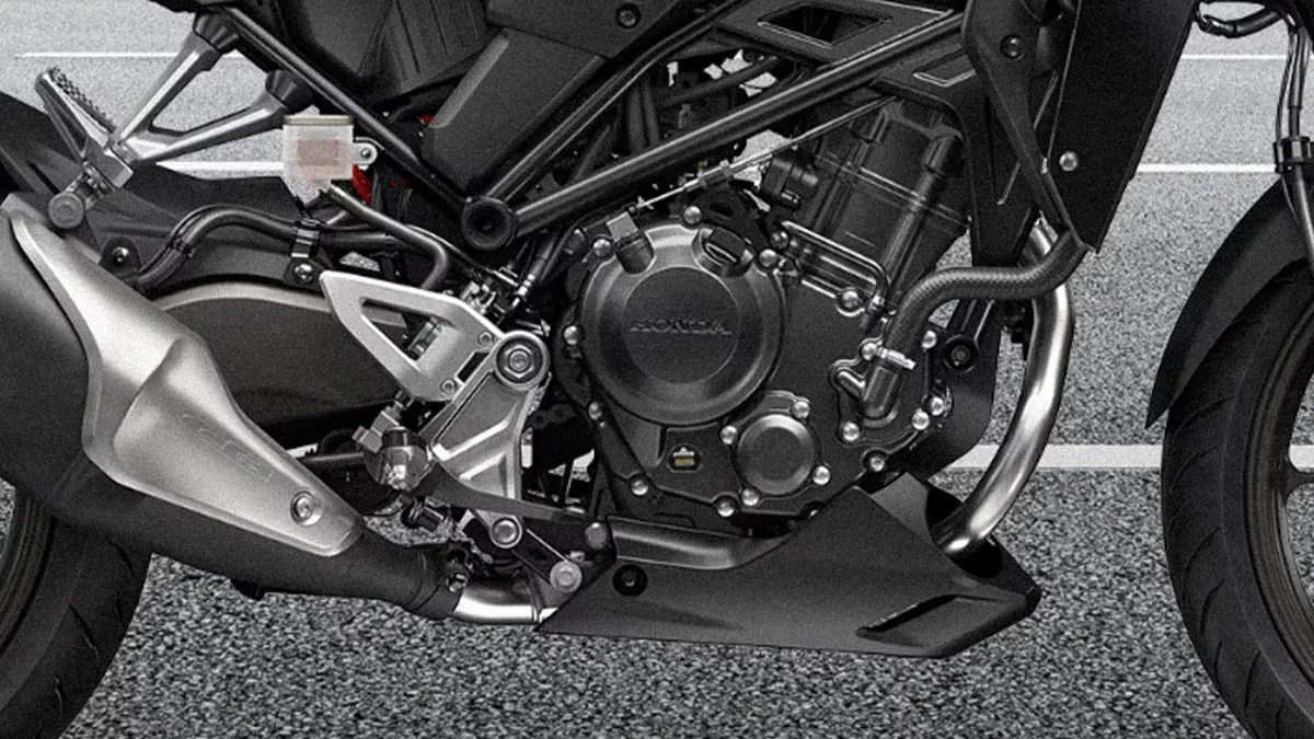 Close-up of a black Honda motorcycle engine and exhaust system with visible frame and footrest.