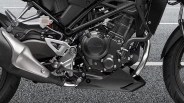 Close-up of a black Honda motorcycle engine and exhaust system with visible frame and footrest.