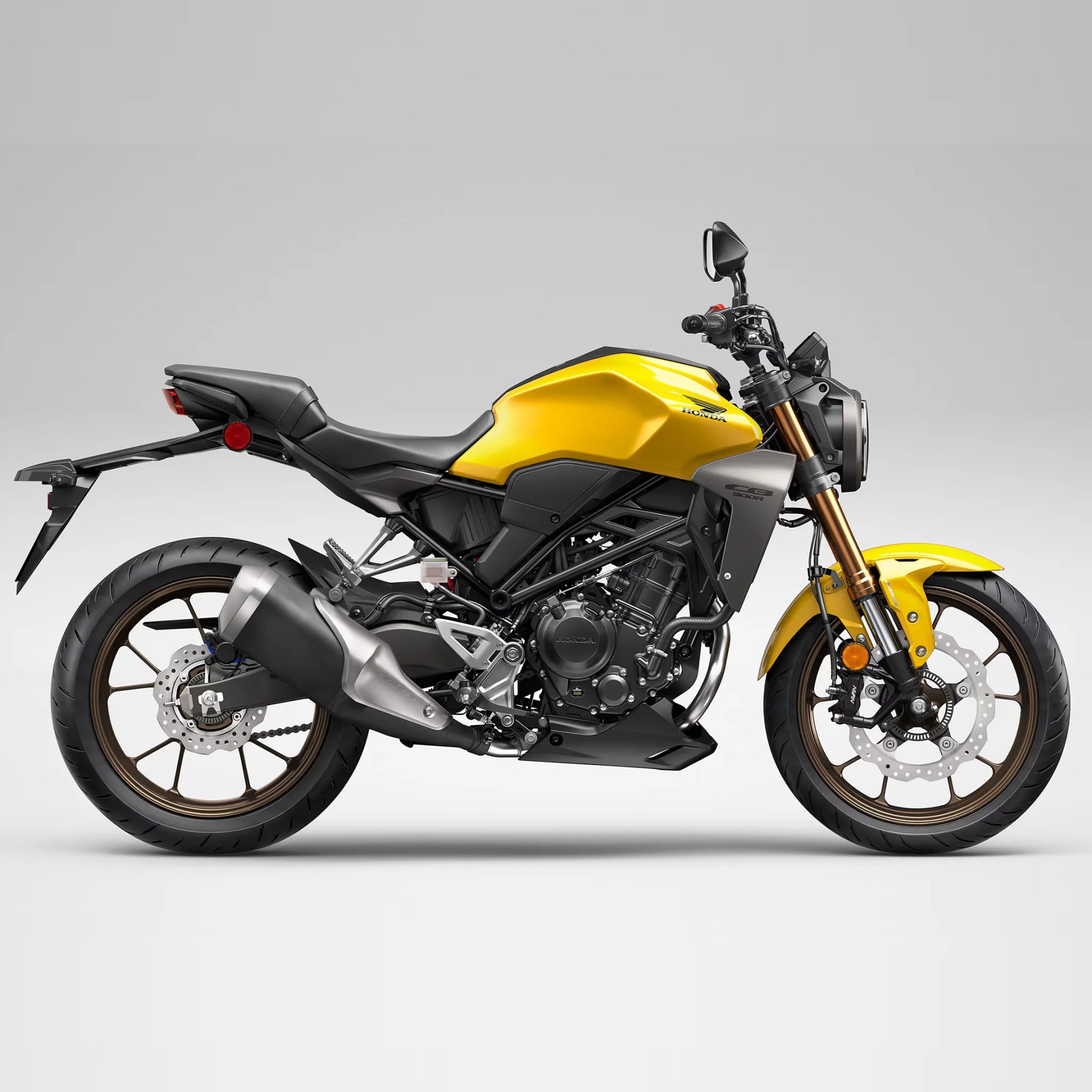 Yellow Honda CB300R motorcycle side view with black seat and bronze front forks.