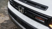 Front grille of a white Honda Passport Trailsport with black accents and orange Trailsport badge.