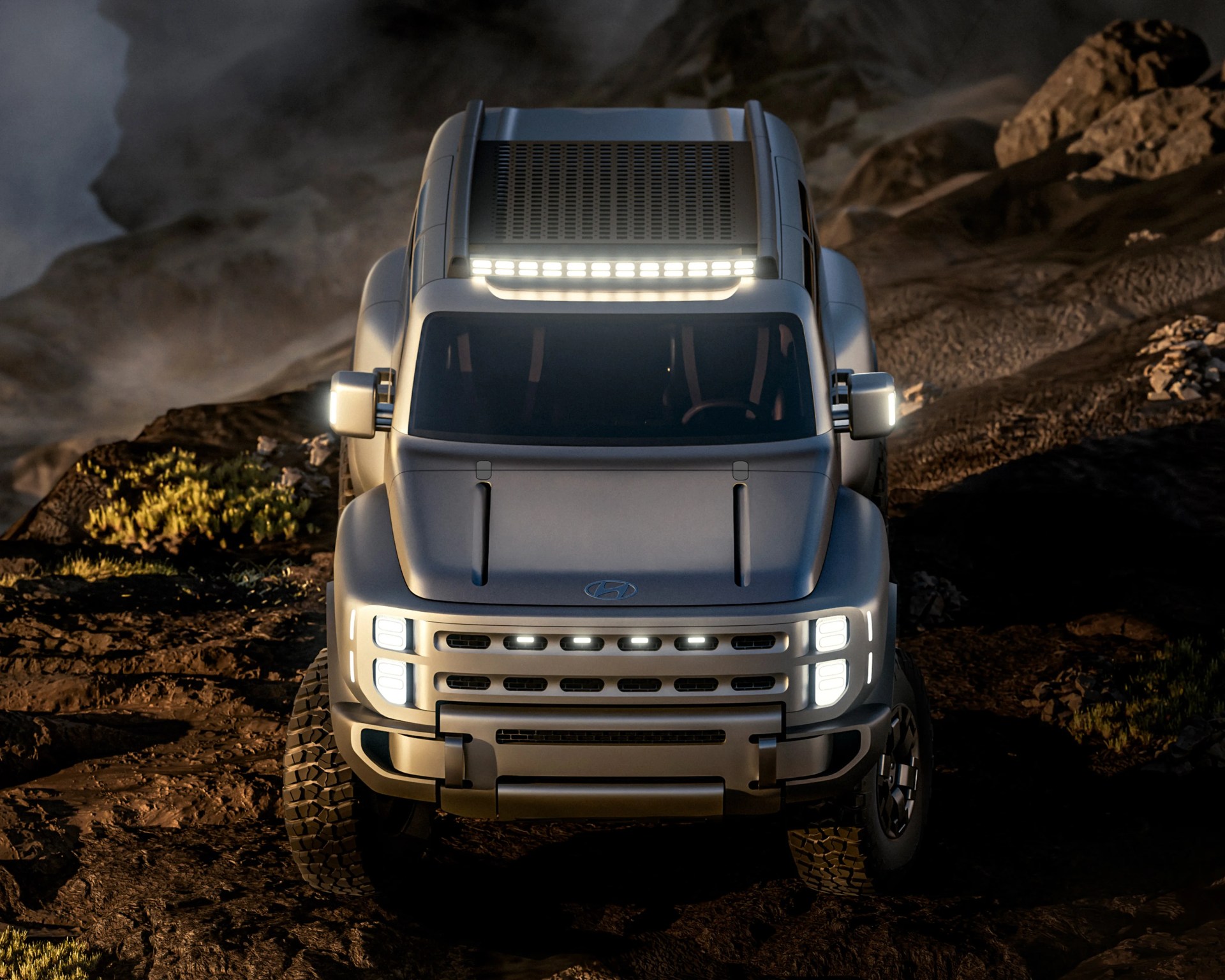 Front view of a silver Hyundai off-road truck with LED lights on a rocky terrain at dusk.