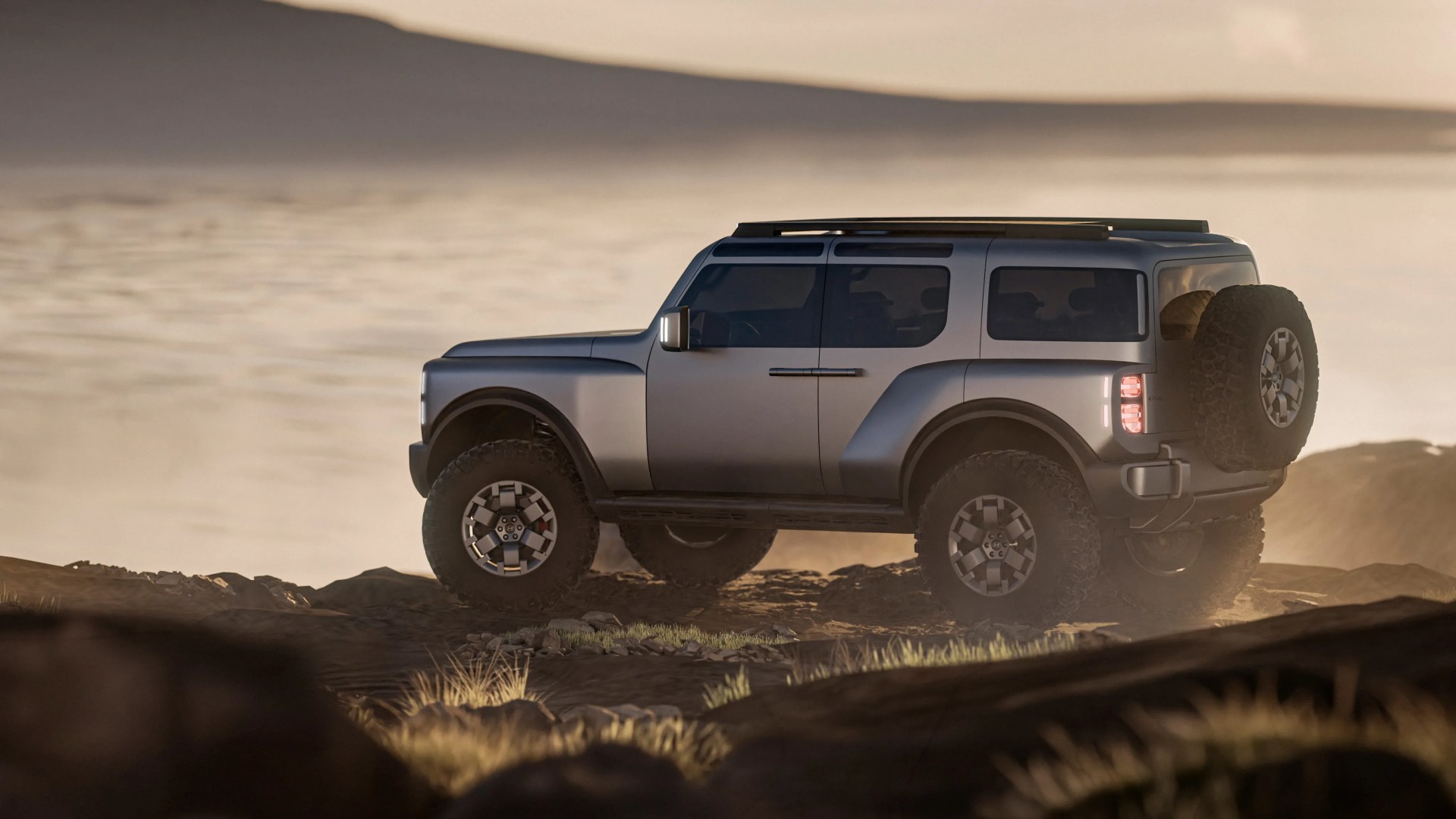 Silver off-road SUV with large tires and roof rack parked on rocky terrain at sunset.