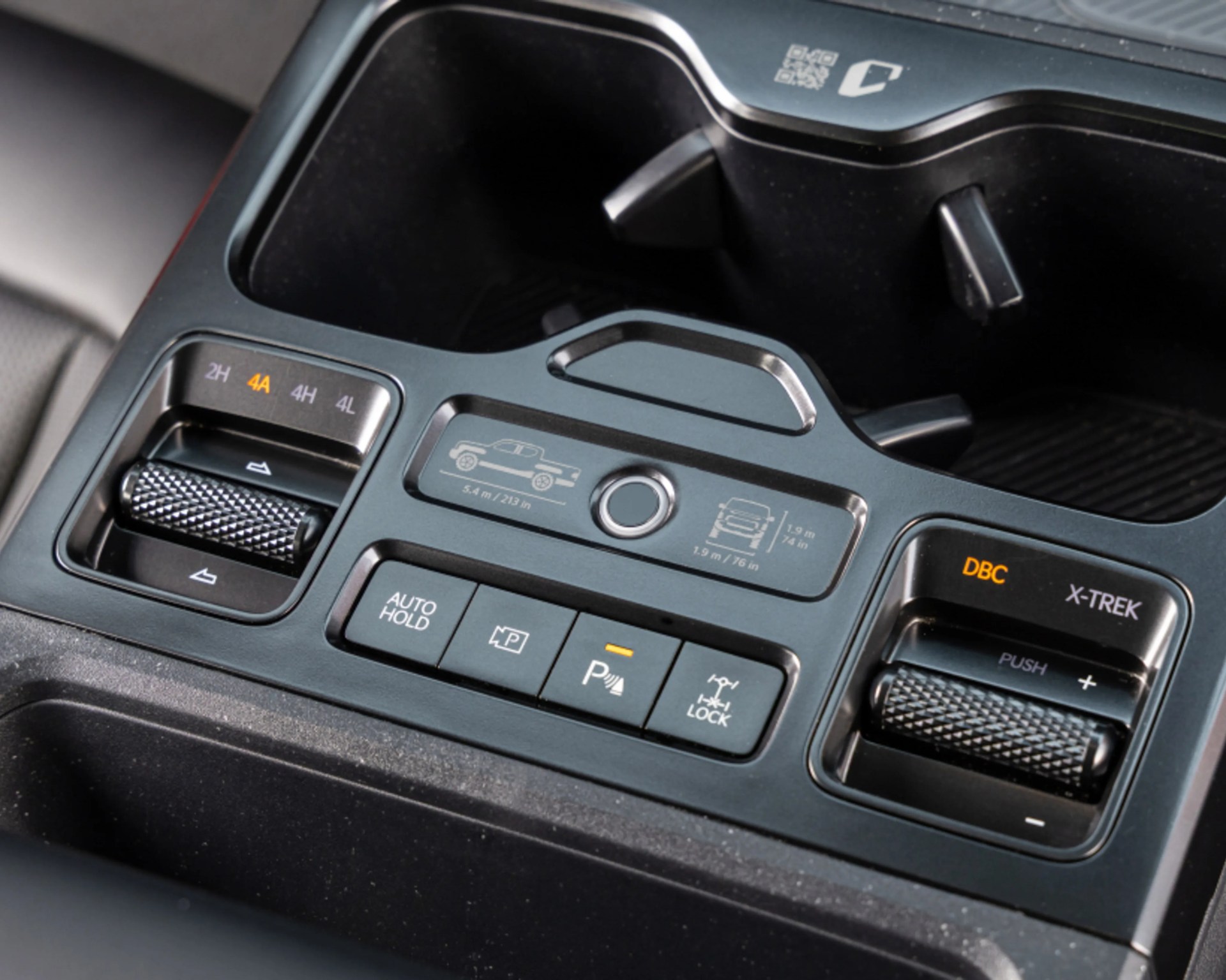 Car center console with control buttons for 4WD modes, auto hold, parking assist, and differential lock.