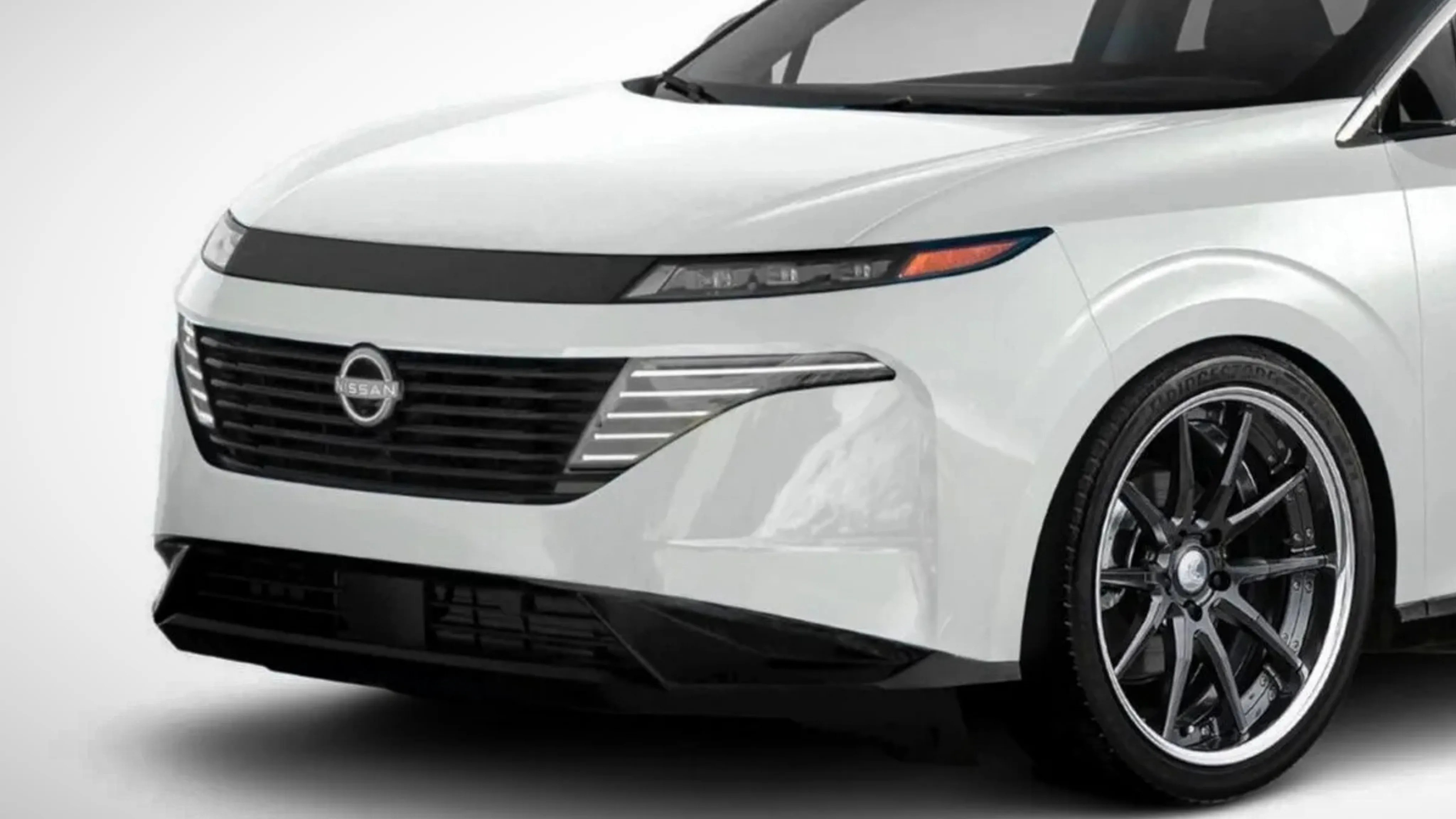 Front view of a white Nissan car showing the grille, headlights, and black alloy wheel.