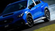 Blue Subaru WRX STI sedan drifting on a racetrack with smoke from rear tires.