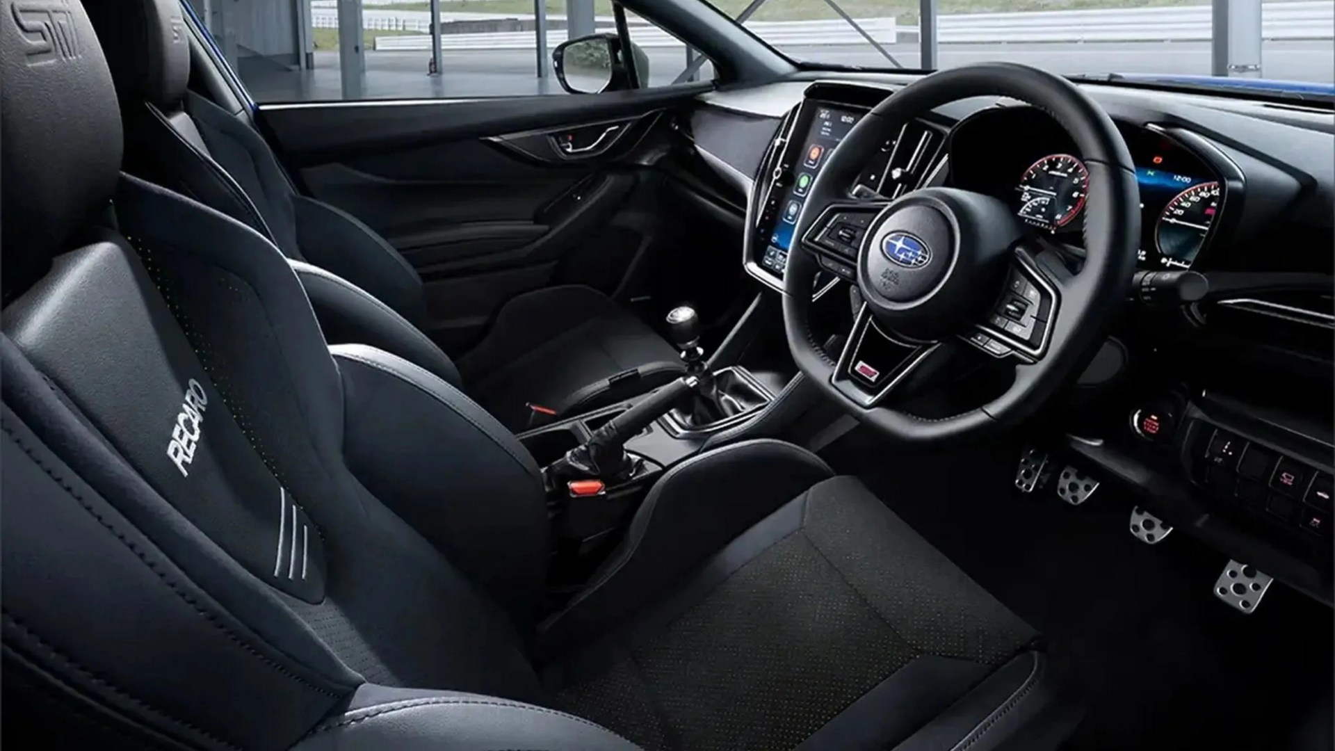 Black Recaro racing seats and a black leather steering wheel inside a Subaru car interior with a manual gear shift.