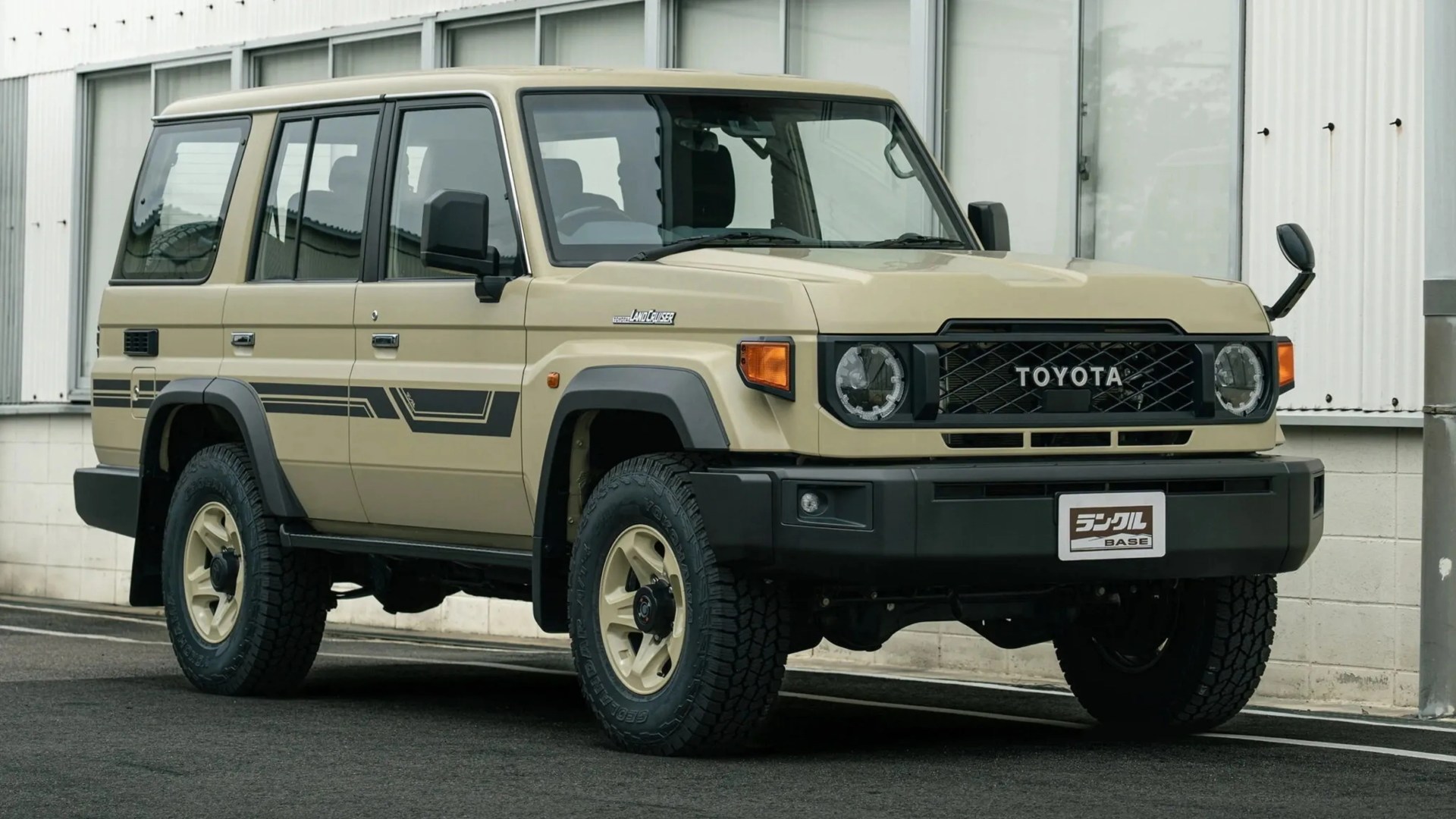 Beige Toyota Land Cruiser SUV with black trim and off-road tires parked in front of a building.