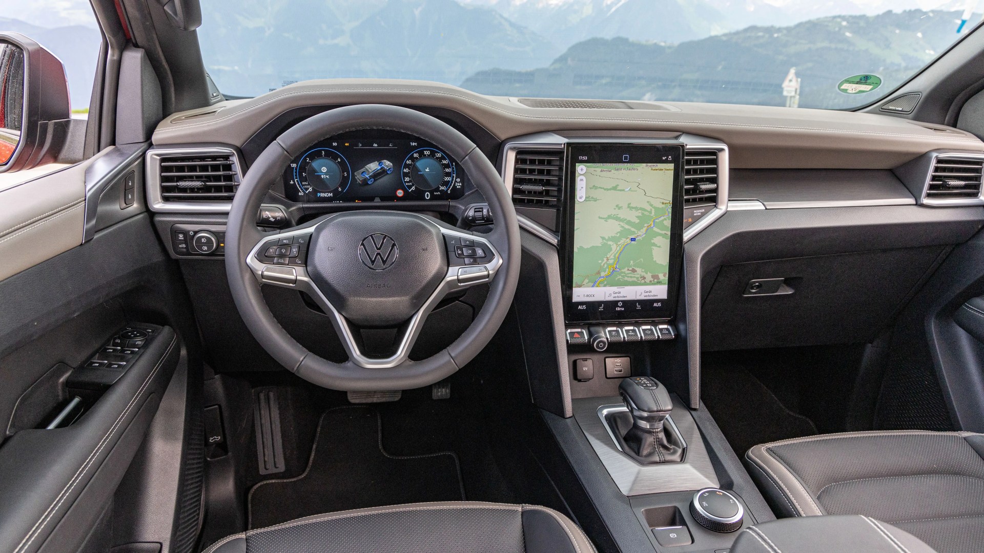 Volkswagen car interior with black leather steering wheel, digital dashboard, and vertical touchscreen navigation display.
