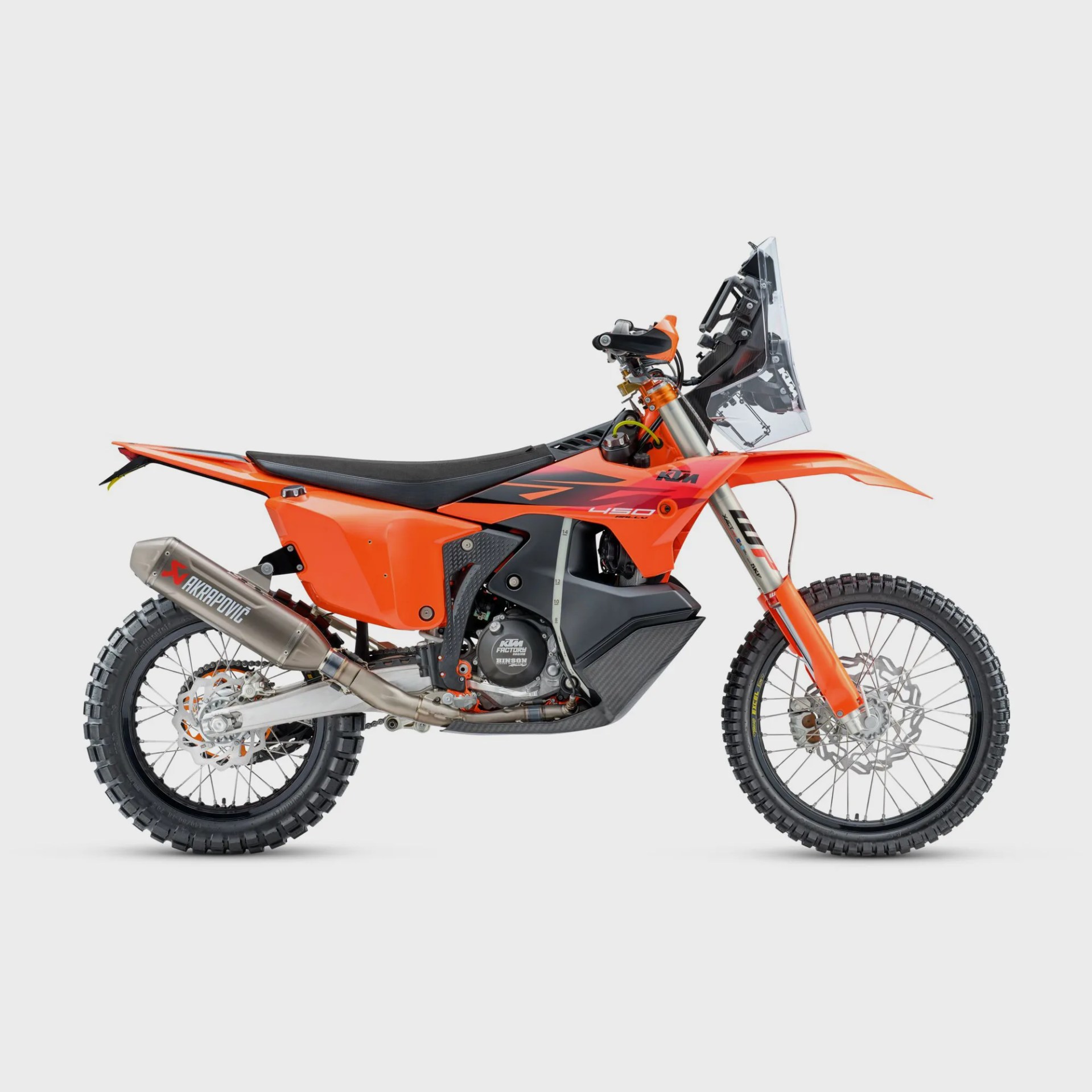 Orange KTM 450 rally motorcycle with black seat, clear windscreen, and knobby tires on a white background.