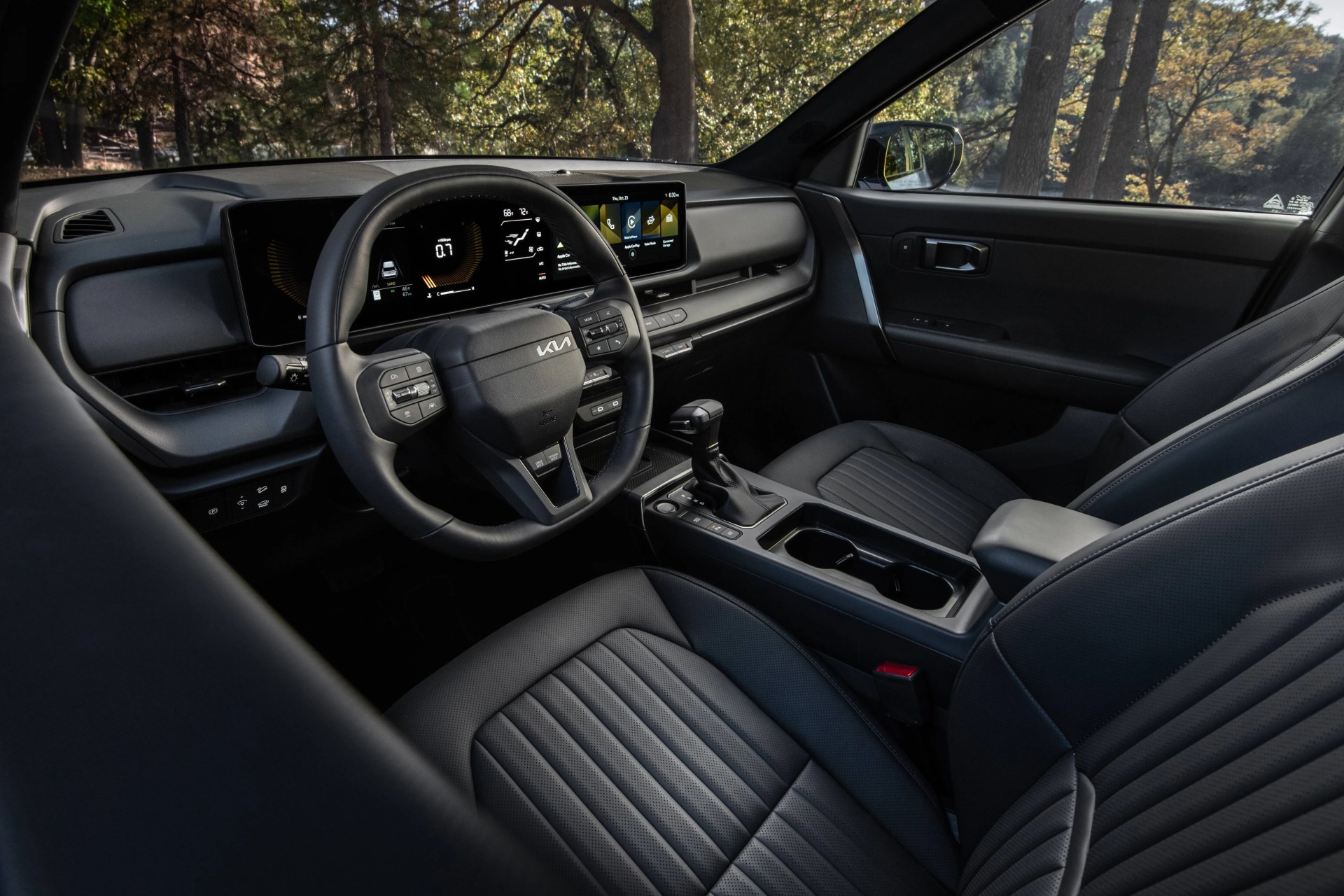 Black leather car interior with digital dashboard, touchscreen display, and center console with gear shift and cup holders.