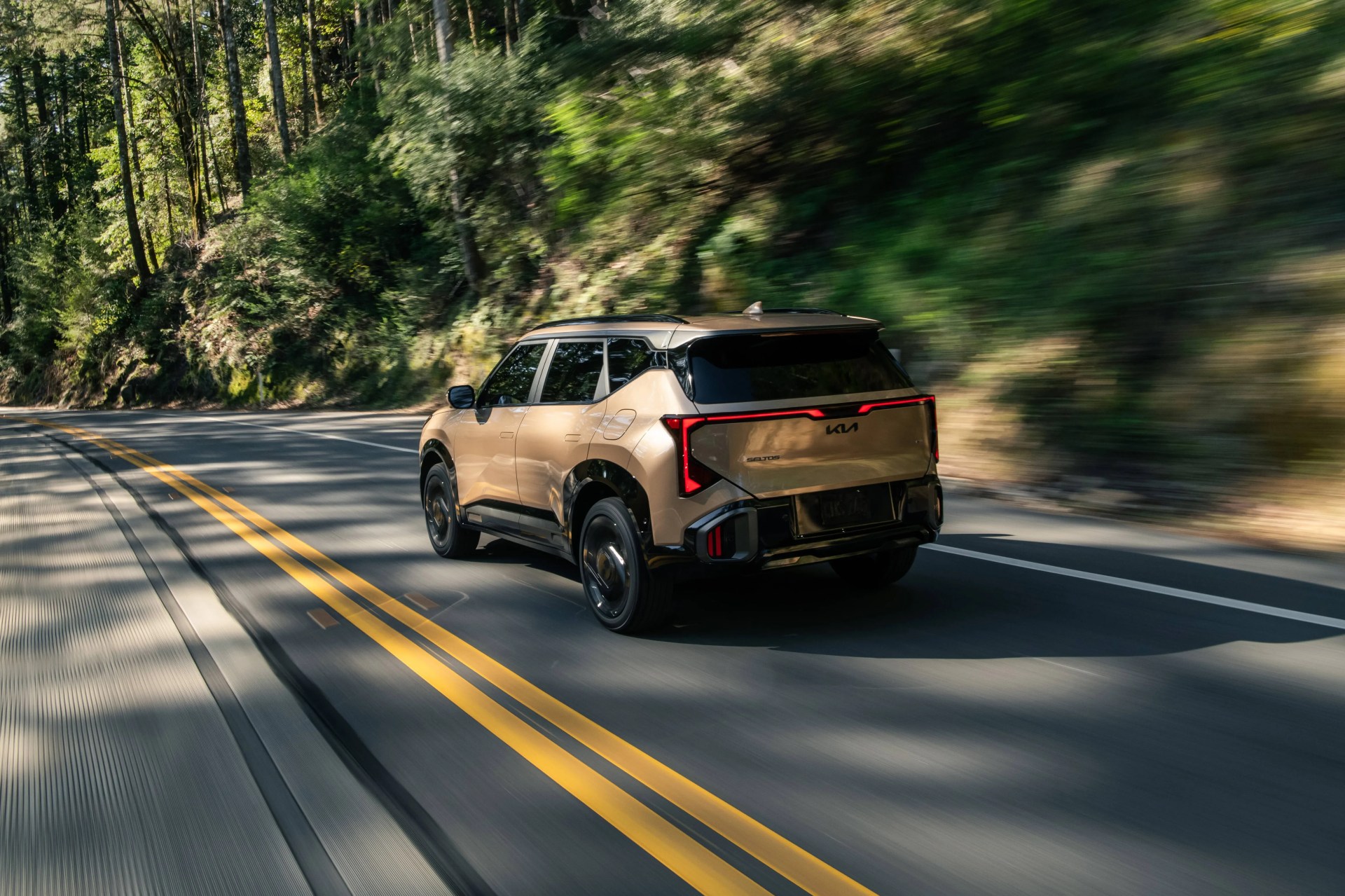 Beige Kia Seltos SUV driving on a forested road with motion blur.
