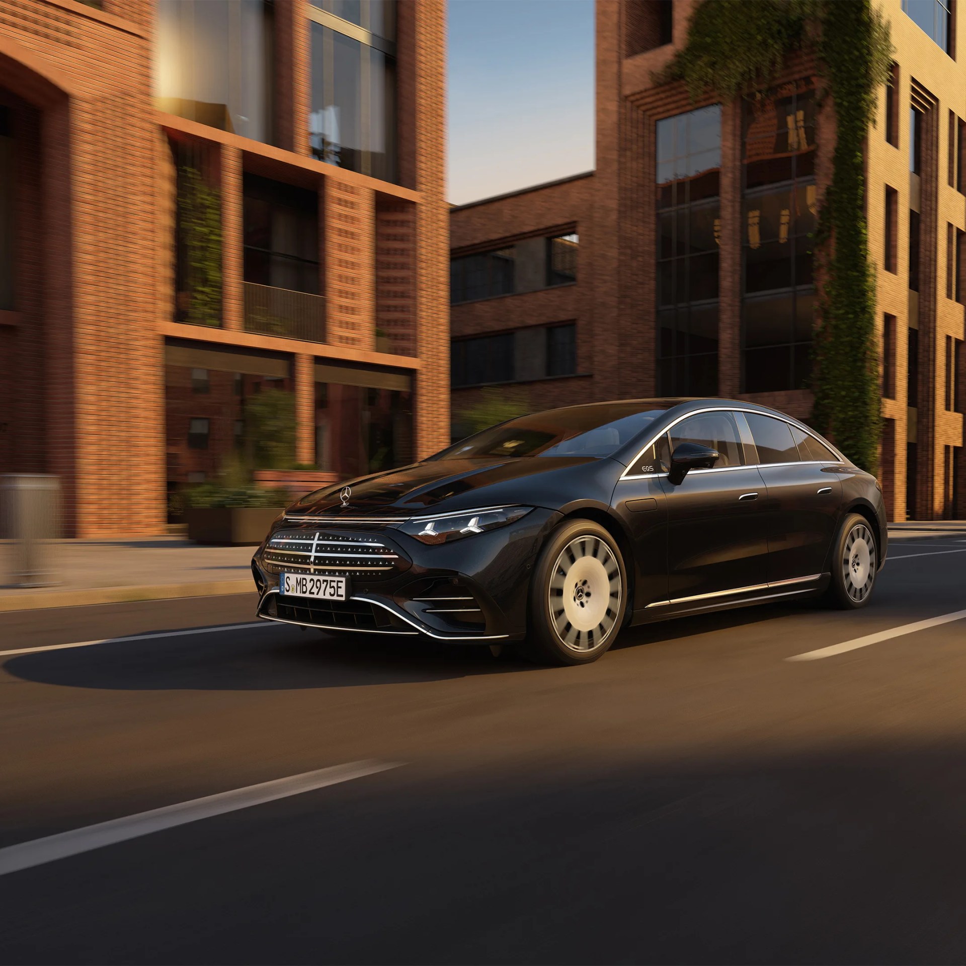Black Mercedes-Benz EQS electric sedan driving on a city street with brick buildings in the background.