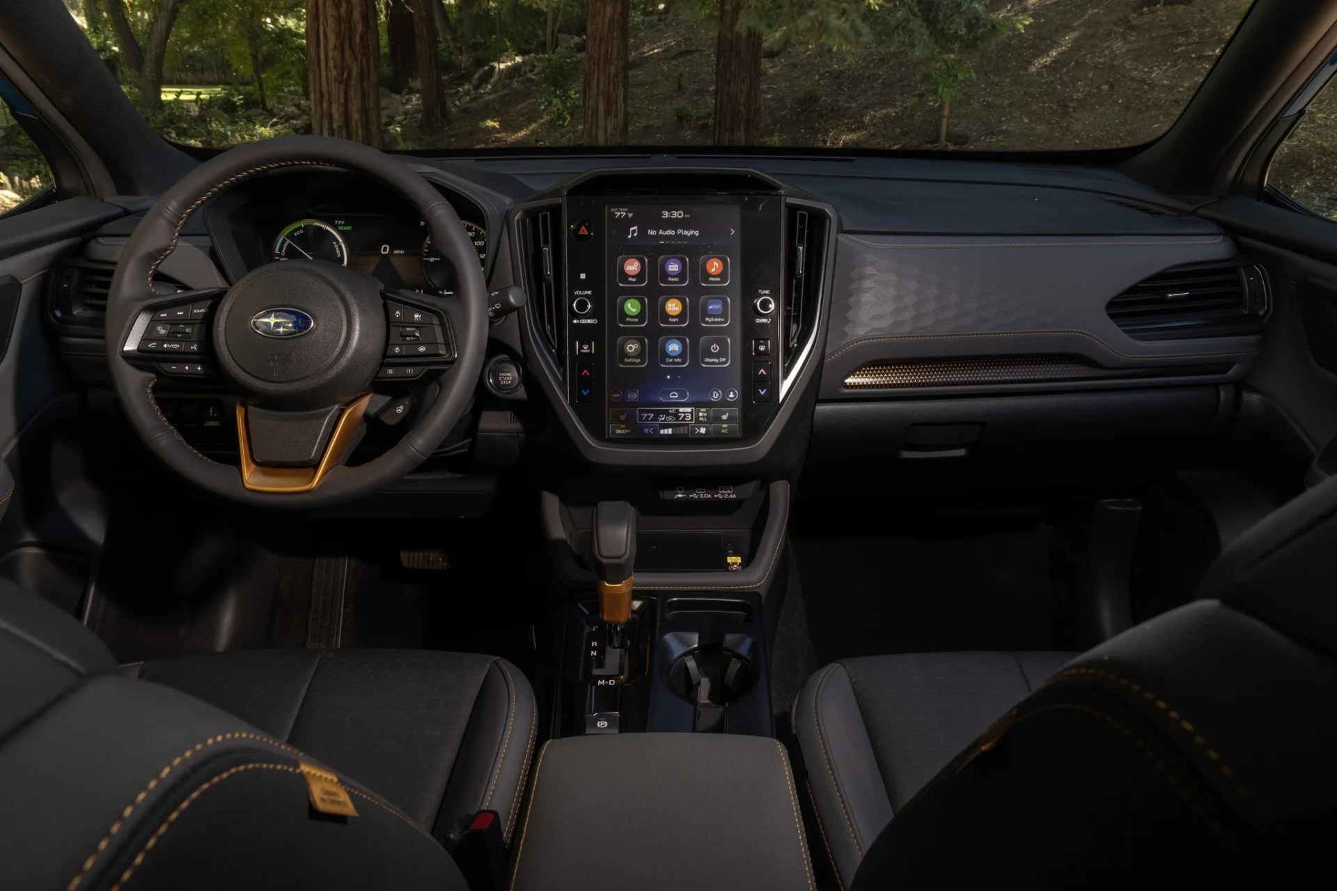 Interior of a Subaru car featuring a black steering wheel with bronze accents, a large vertical touchscreen, and black seats with bronze stitching.