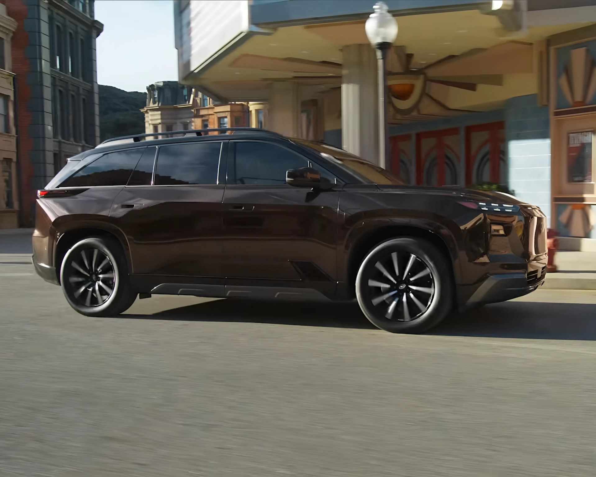 Dark brown electric SUV with black alloy wheels parked on a city street.
