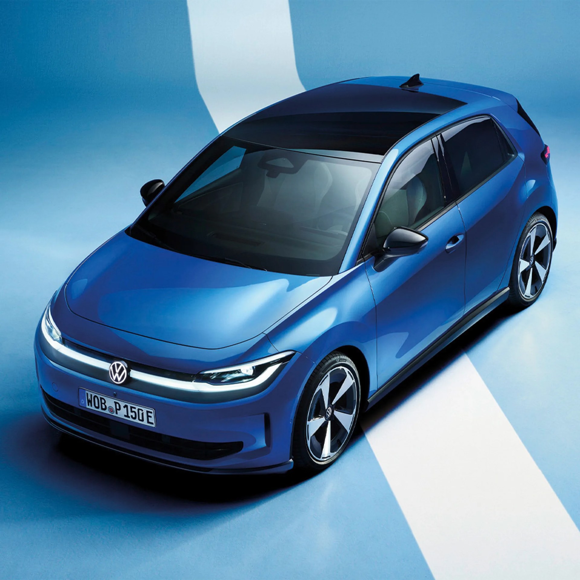 Blue Volkswagen electric hatchback with black roof and LED headlights on blue and white floor.