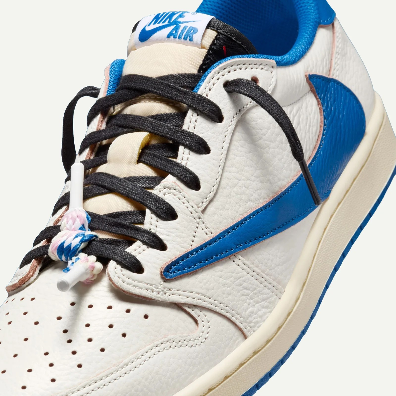 Close-up of a white leather Nike Air sneaker with blue swoosh, black laces, and a braided lace knot.