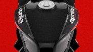 Close-up of a black Aprilia Racing motorcycle fuel tank against a red background.