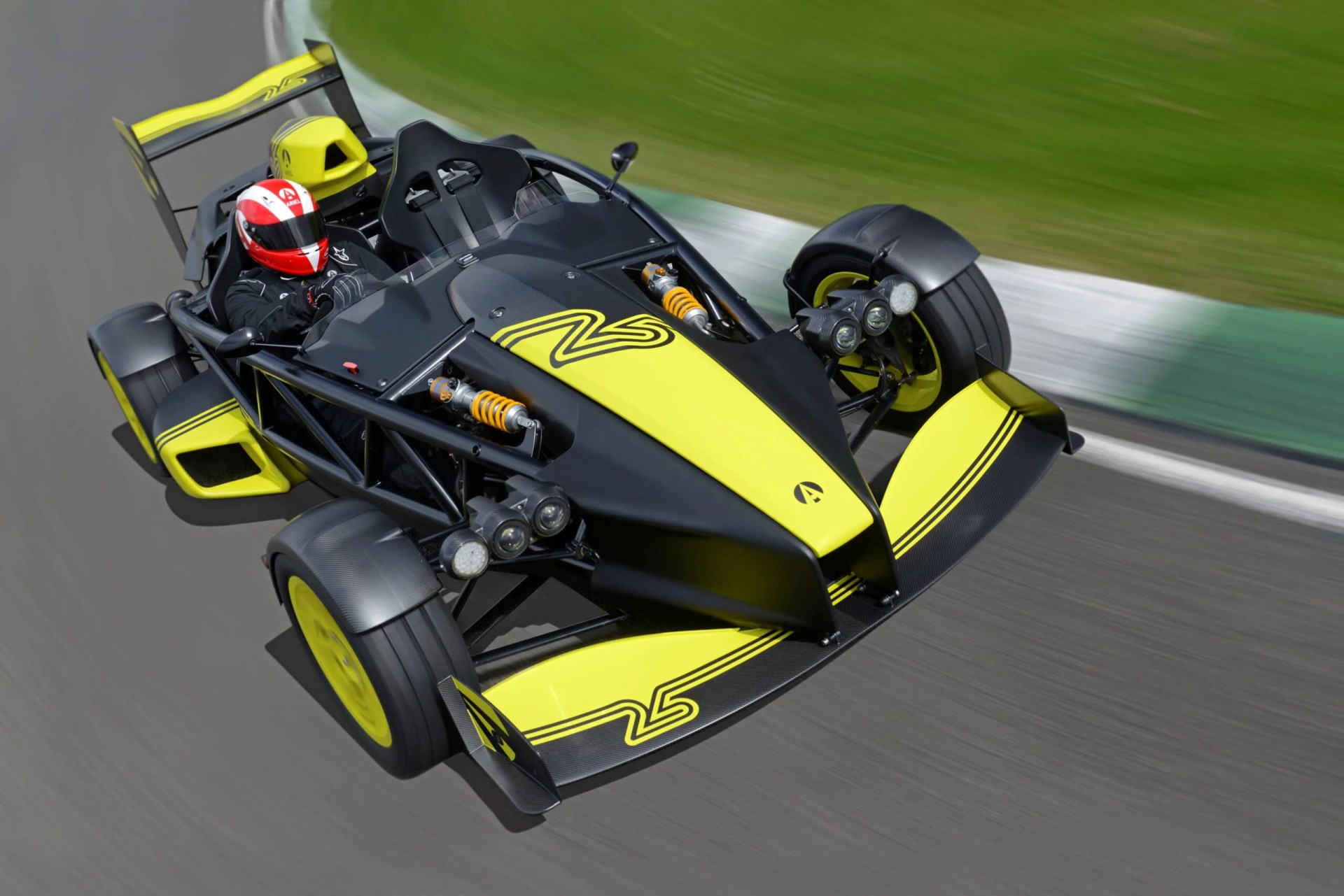 Black and yellow open-wheel race car with exposed suspension and a driver wearing a red and white helmet on a racetrack.