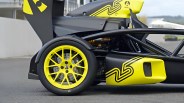 Close-up of a yellow and black Ariel car rear wheel with yellow multi-spoke rim and visible suspension components.