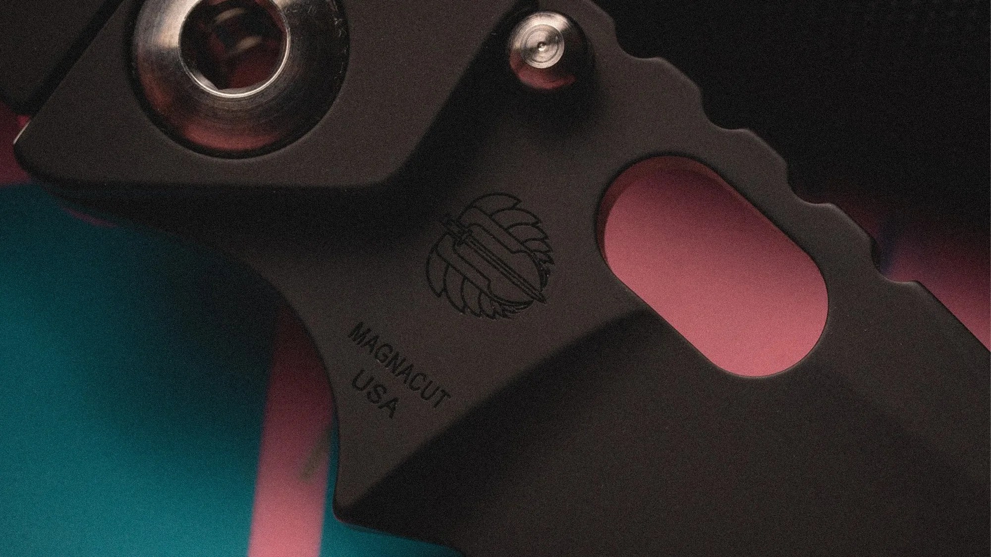 Close-up of a black metal tool with a circular hole, engraved logo, and "MAGNACUT USA" text.