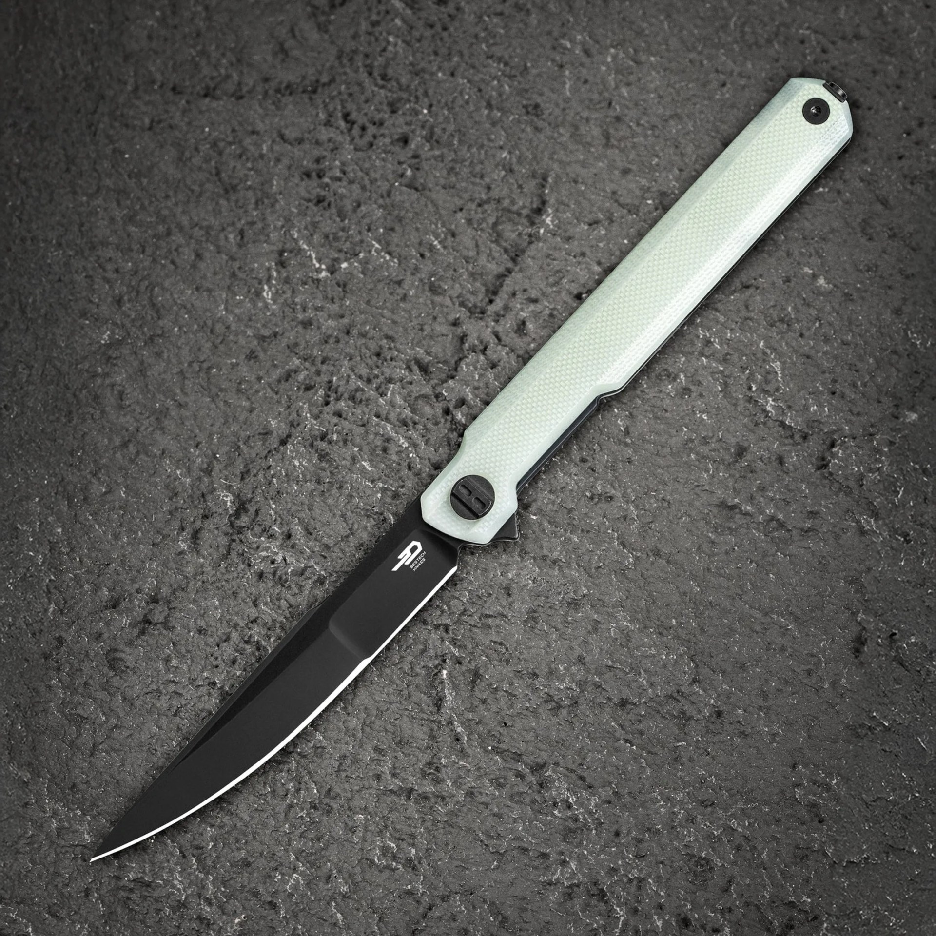 Black folding knife with a slim, curved blade and a textured light green handle on a dark textured surface.