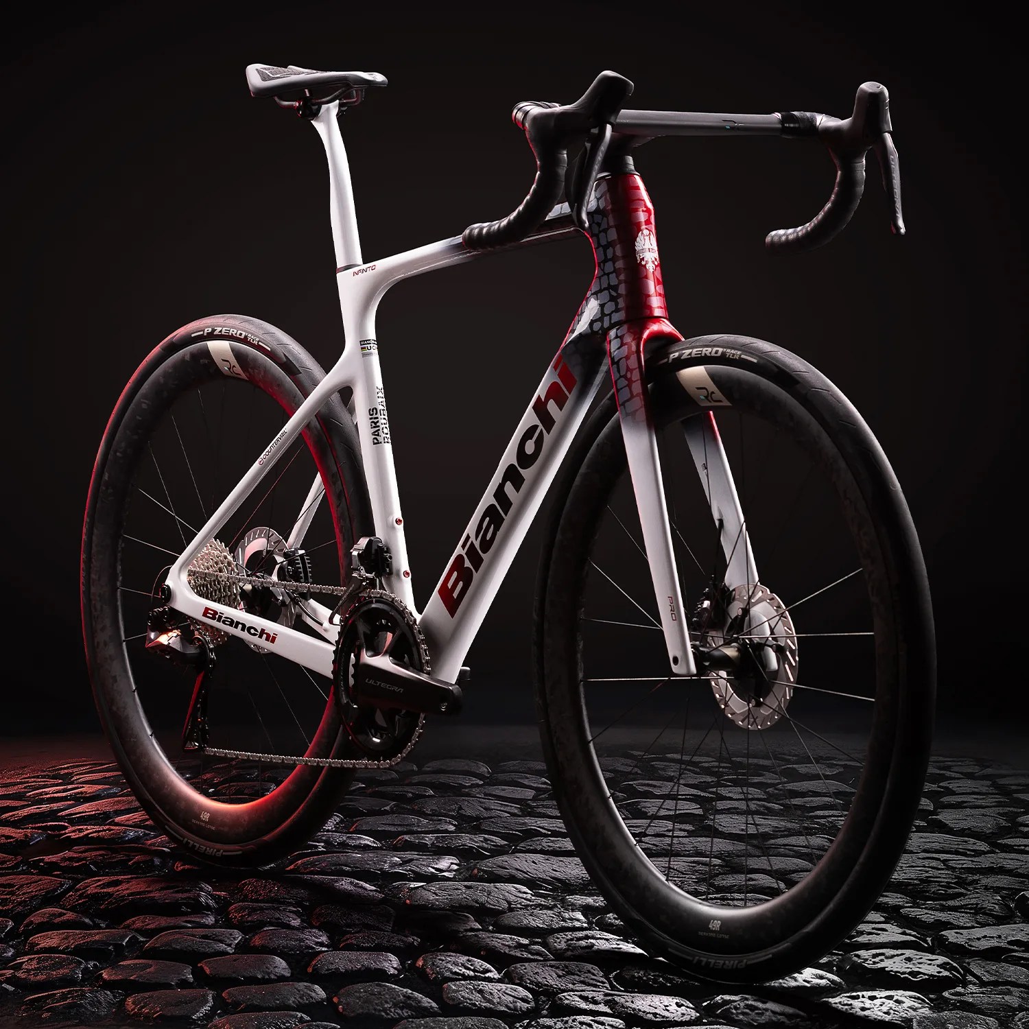 White and red Bianchi road bike with drop handlebars and disc brakes on cobblestone ground.