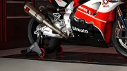 Close-up of a red, white, and black Bimota motorcycle exhaust and rear wheel on a black and red stand.