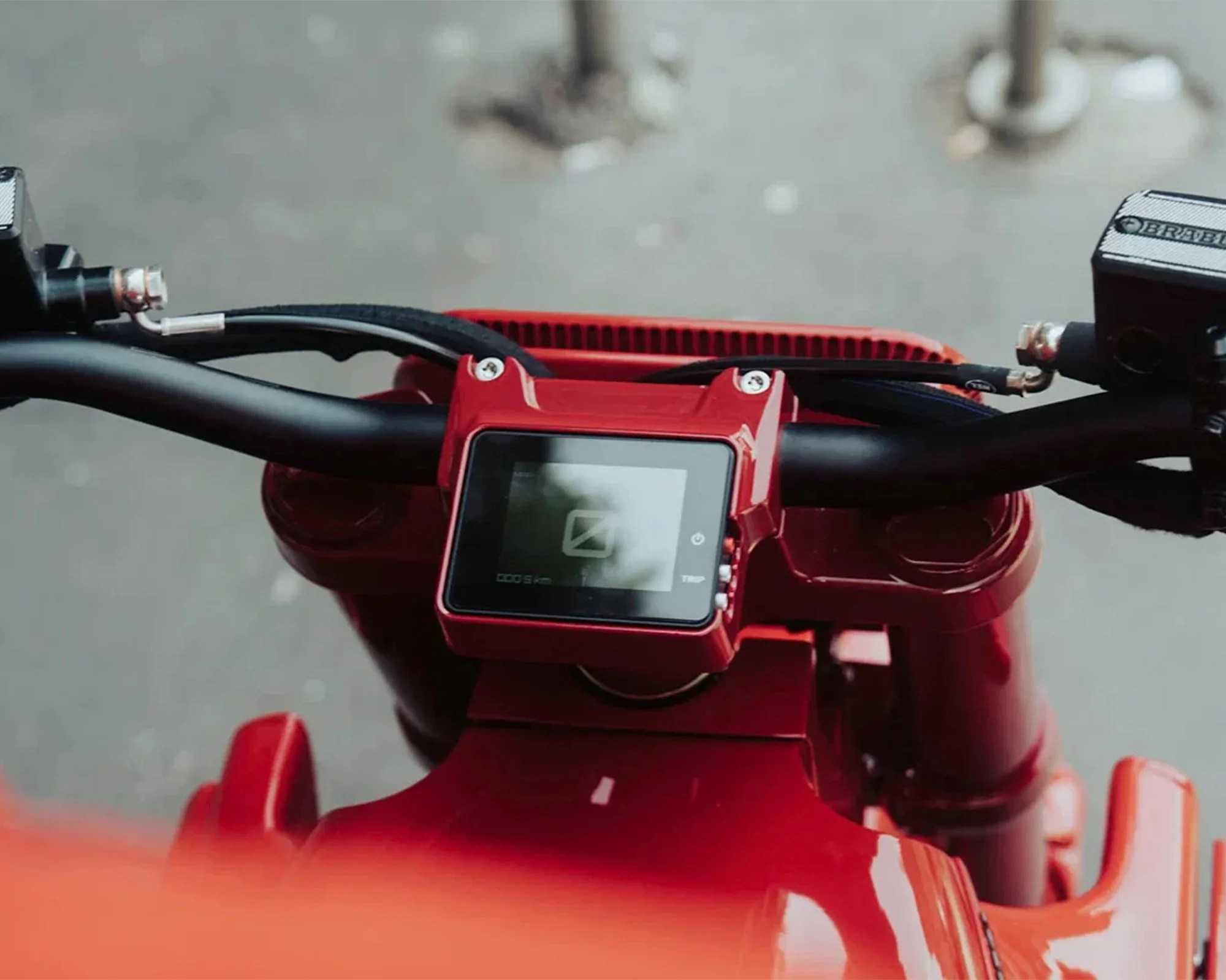 Close-up of red electric scooter handlebars with digital display and brake cables.
