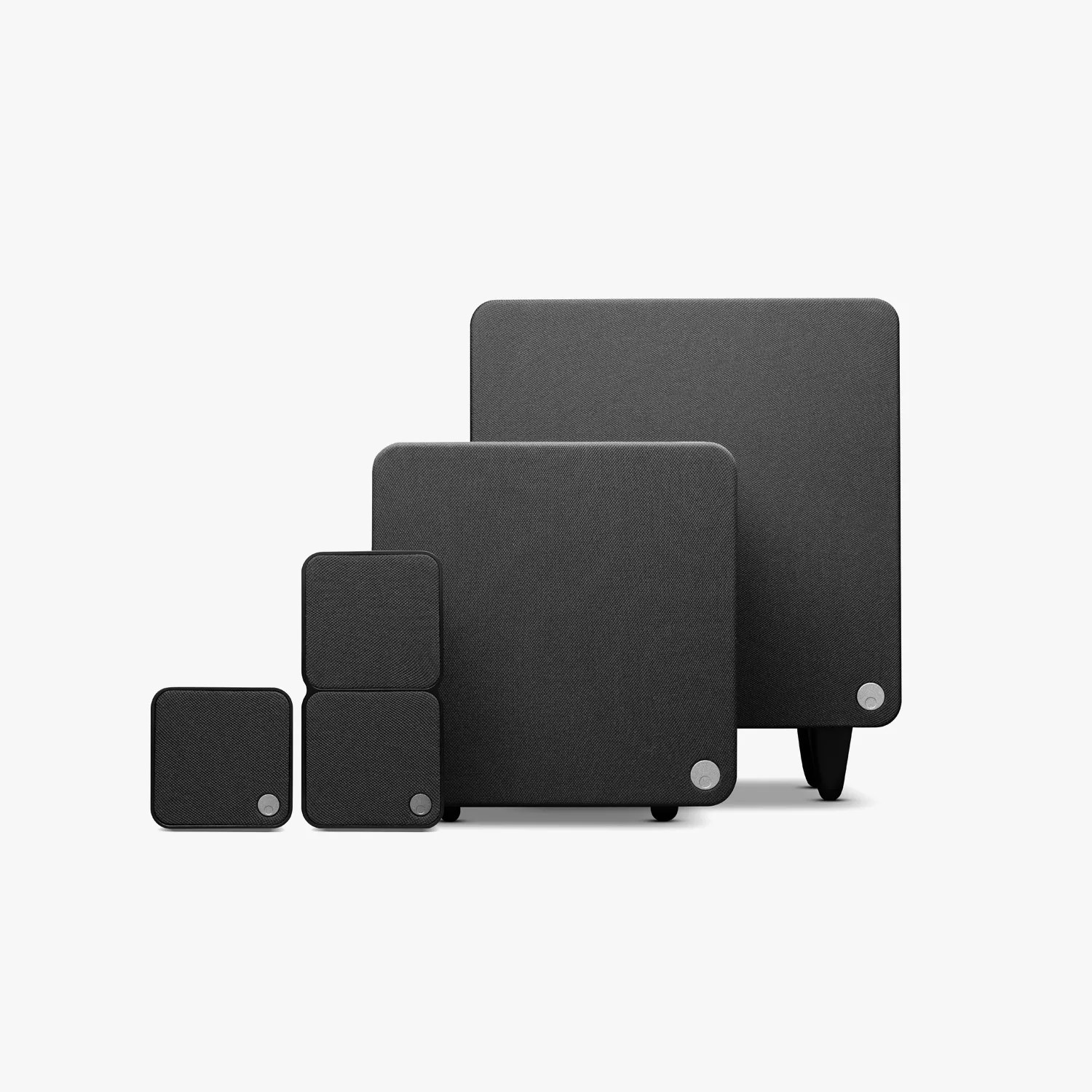 Set of four black fabric-covered square speakers of varying sizes arranged in a row on a white background.