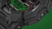 Close-up of a black digital watch with a green display, showing "SHOCK RESIST" and a textured "START" button.