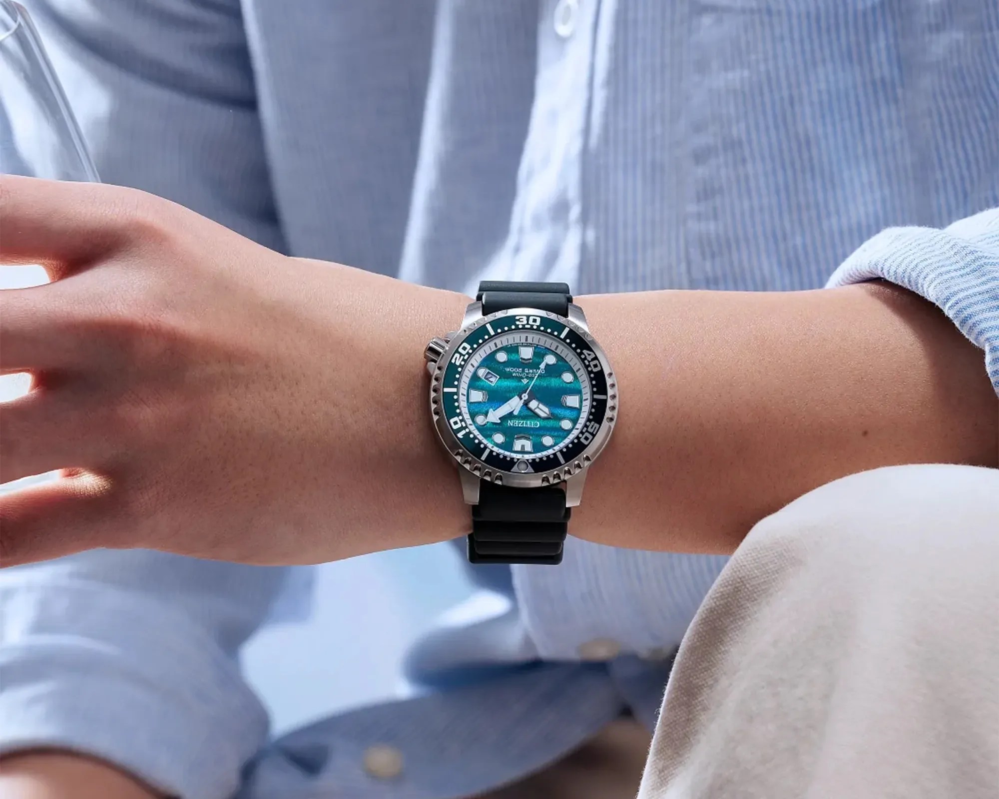 Silver dive watch with a blue textured dial and black rubber strap worn on a wrist.