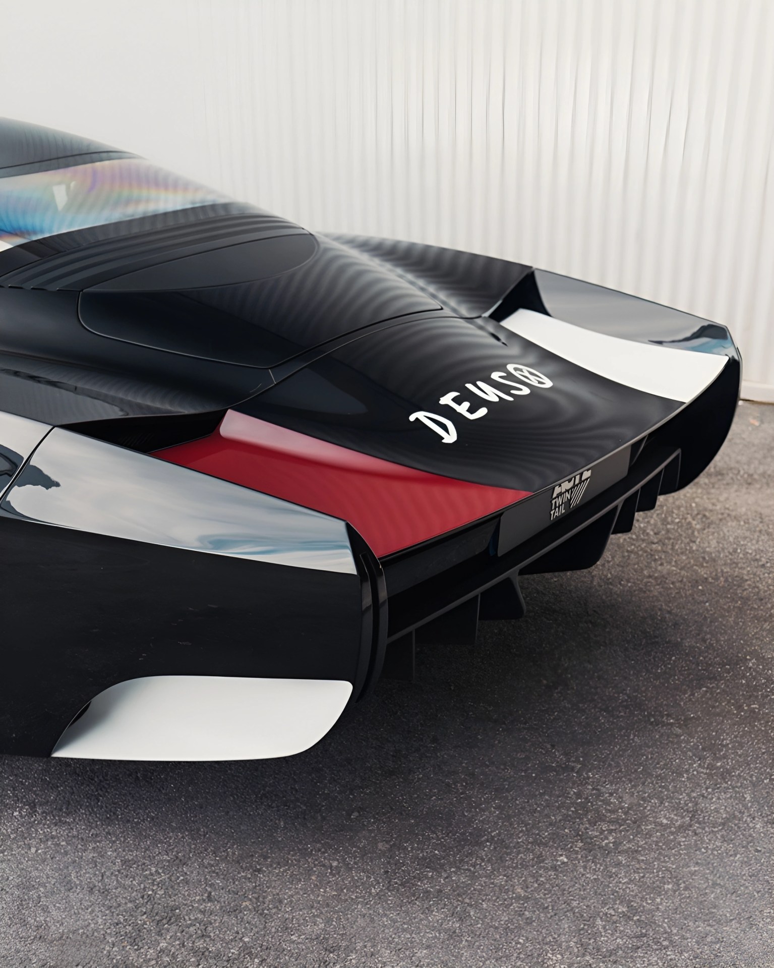 Rear view of a sleek black and white sports car with red accents and "DENSO" branding on the back.