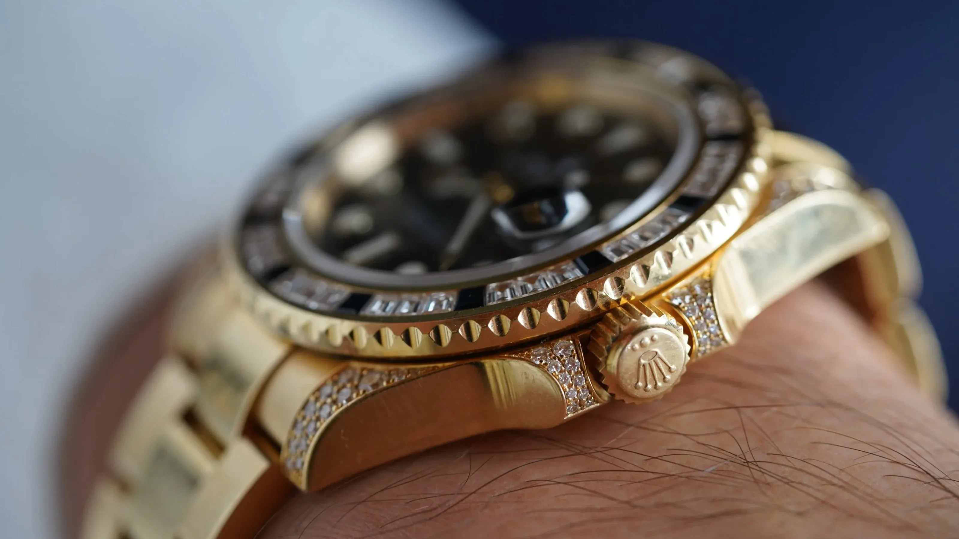 Close-up of a gold Rolex watch with diamond accents on the bezel and bracelet, worn on a wrist.