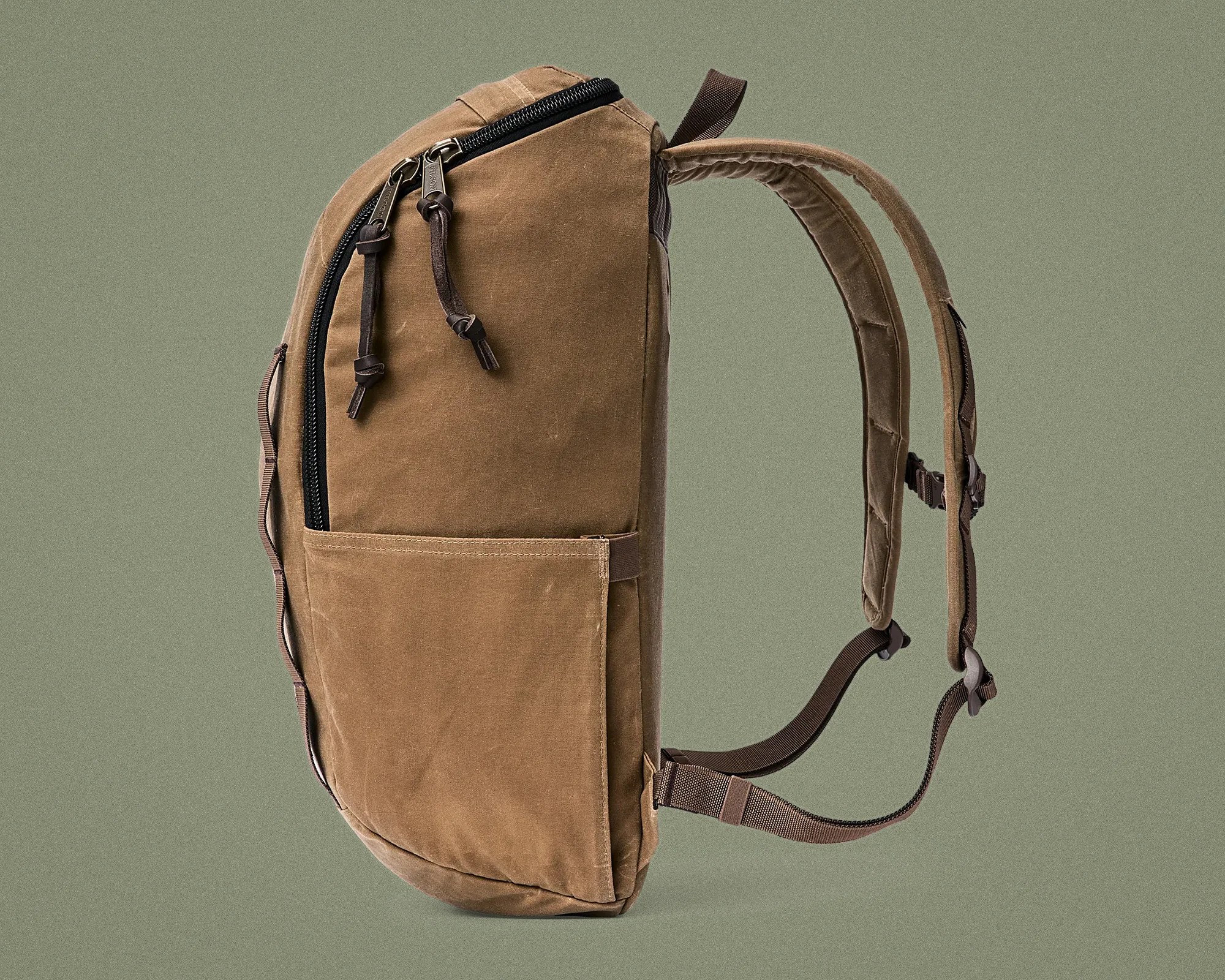 Brown canvas backpack with padded shoulder straps and front pocket on a green background.